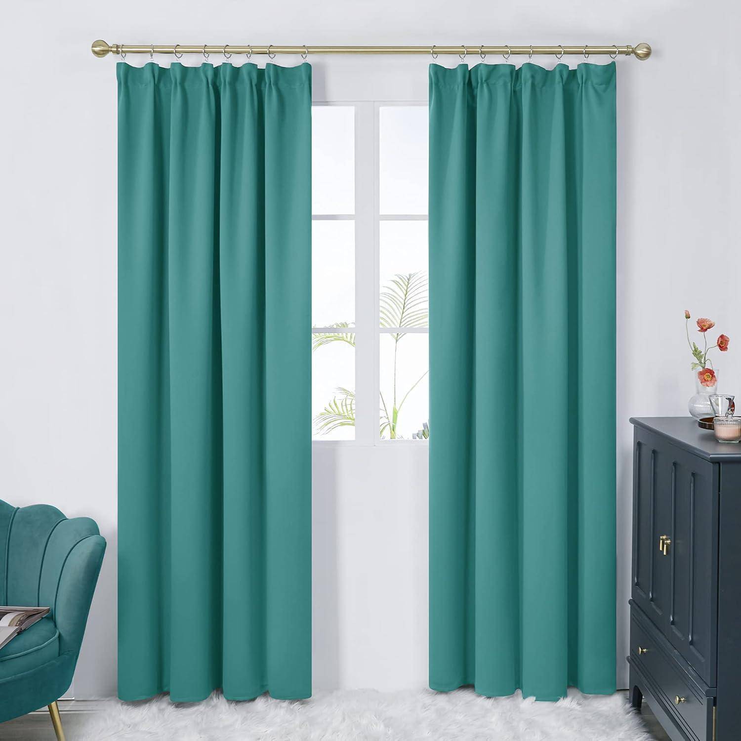 Grüne Vorhänge hängen an einer goldenen Stange und rahmen ein Fenster mit Blick auf Palmenblätter. Ein grüner Stuhl und ein schwarzer Schrank mit Deko stehen in der Nähe.
