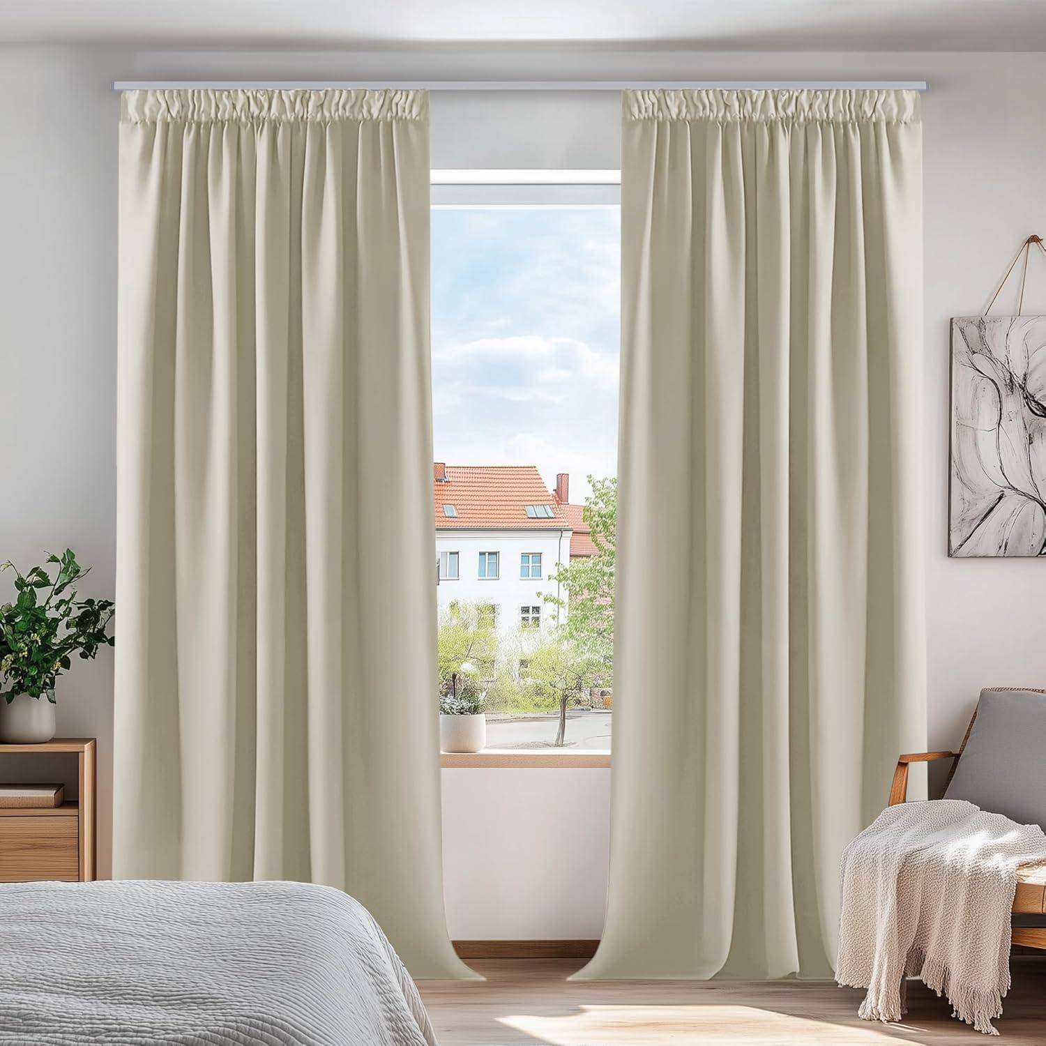 Ein gemütliches Schlafzimmer zeigt ein Fenster mit beigen Vorhängen, einen sonnigen Ausblick nach draußen, ein Bett mit einer weißen Decke und ein gerahmtes Bild an der Wand.