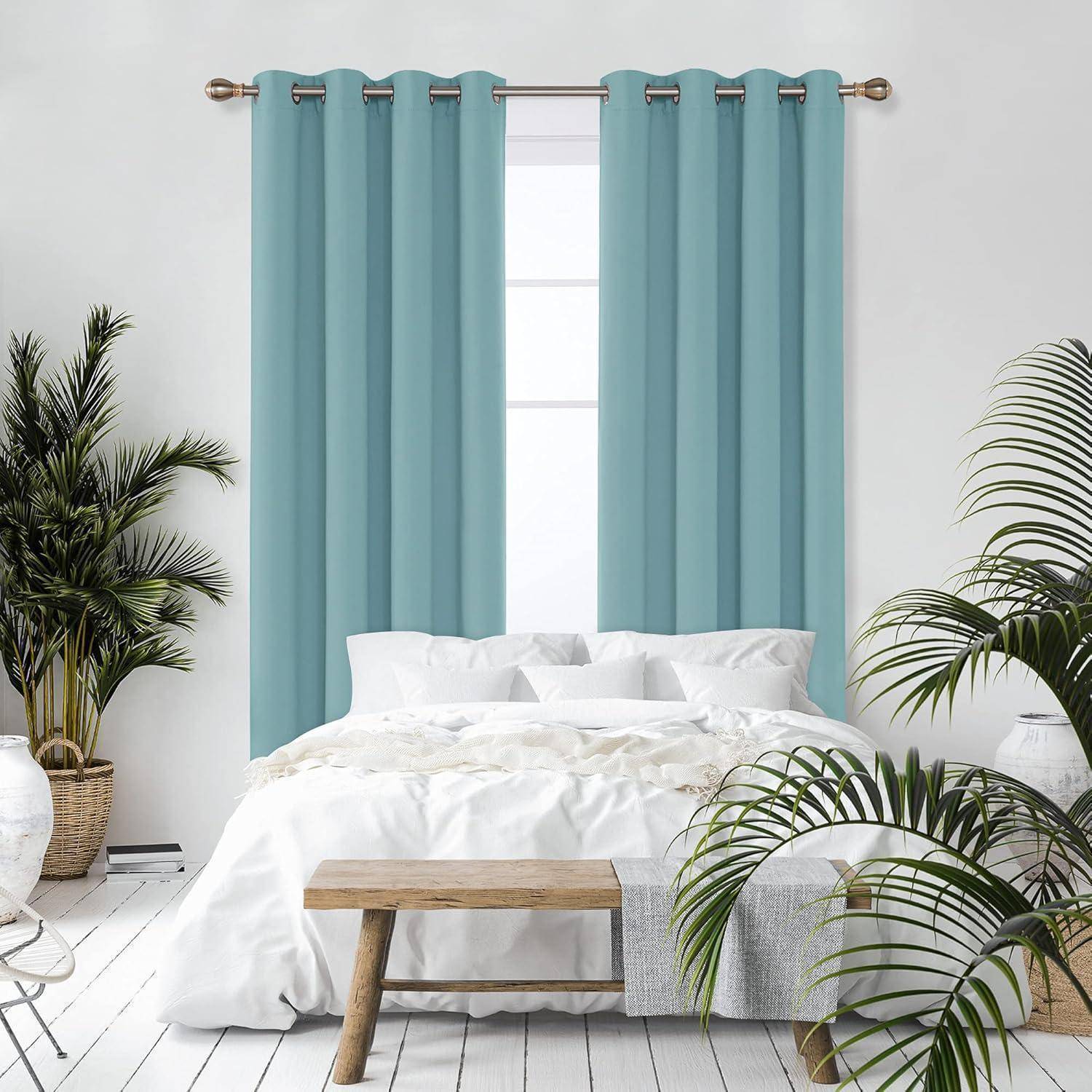 Ein heller Schlafraum zeigt ein weißes Bett mit blauen Vorhängen am Fenster, umgeben von Topfpflanzen und einer Holzbank am Fußende des Bettes.