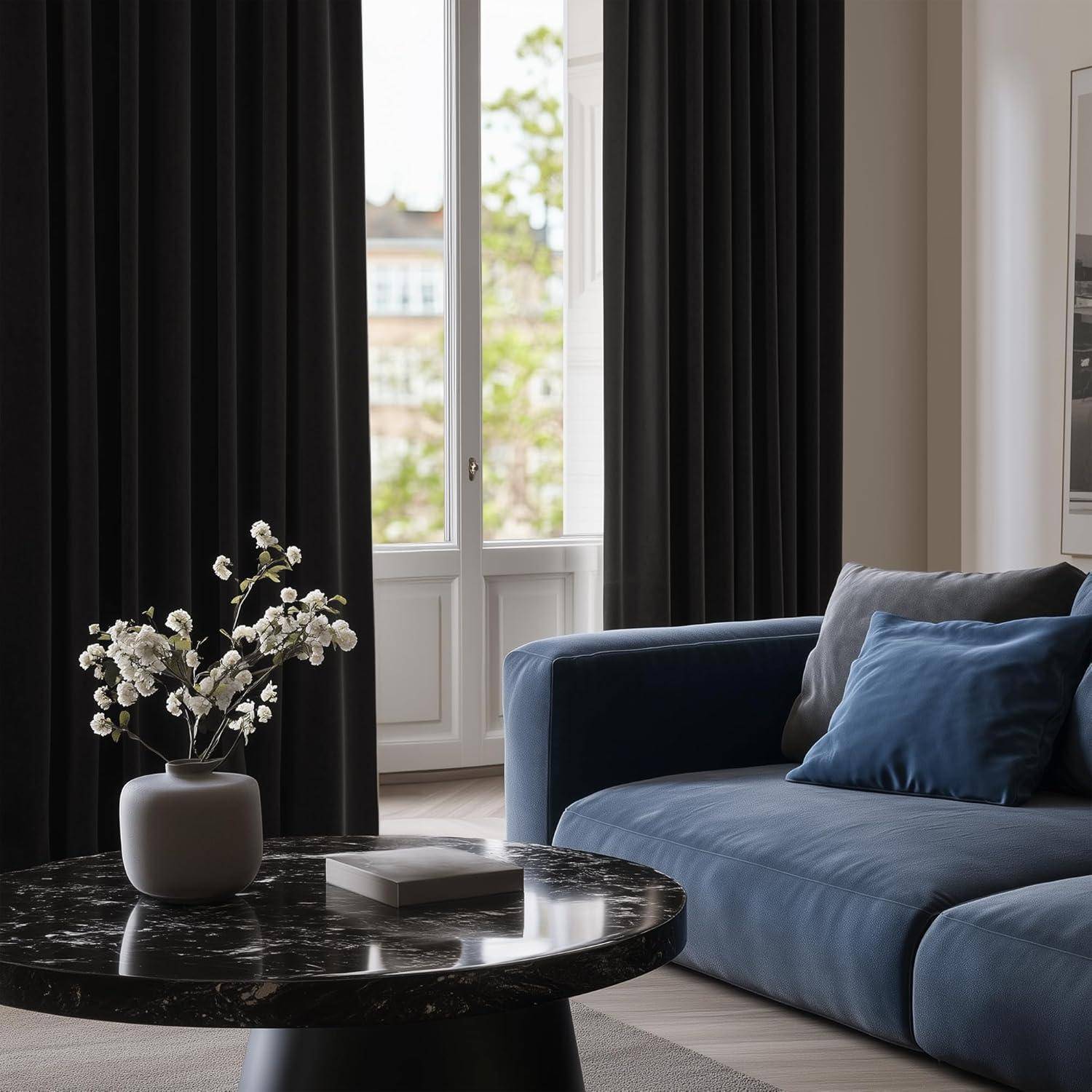 Ein modernes Wohnzimmer mit einem blauen Sofa, einem runden schwarzen Marmor-Couchtisch und einer Vase mit weißen Blumen. Große Fenster mit dunklen Vorhängen.