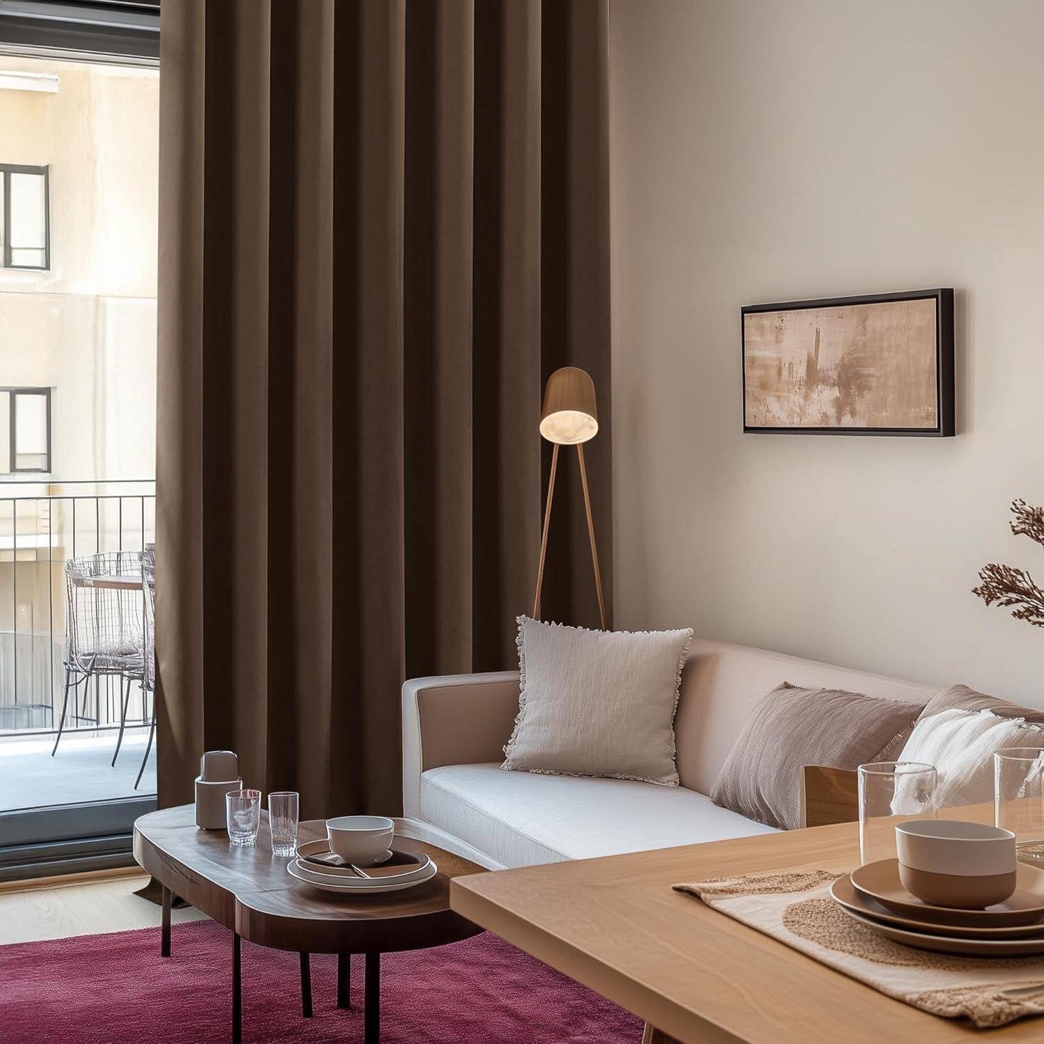 Ein gemütliches Wohnzimmer mit einem weißen Sofa, einem Couchtisch für zwei Personen, Wandkunst, einer Lampe und einem Blick auf den Balkon durch Glastüren. Warme, neutrale Töne.