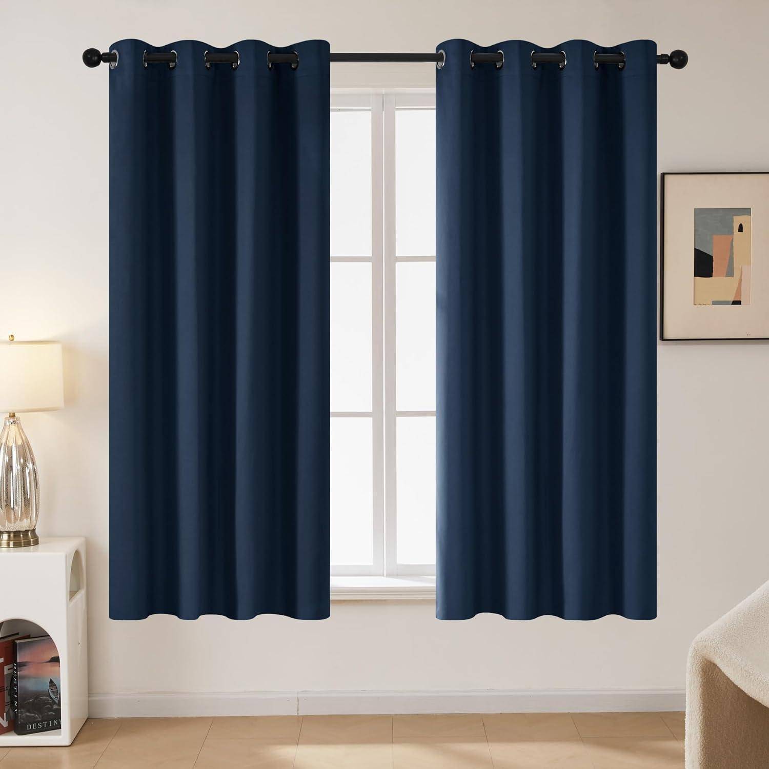 Marineblau-Vorhänge hängen in einem modernen Wohnzimmer und rahmen ein Fenster mit natürlichem Licht ein. Eine Lampe und Wandkunst schmücken den stilvollen Raum.