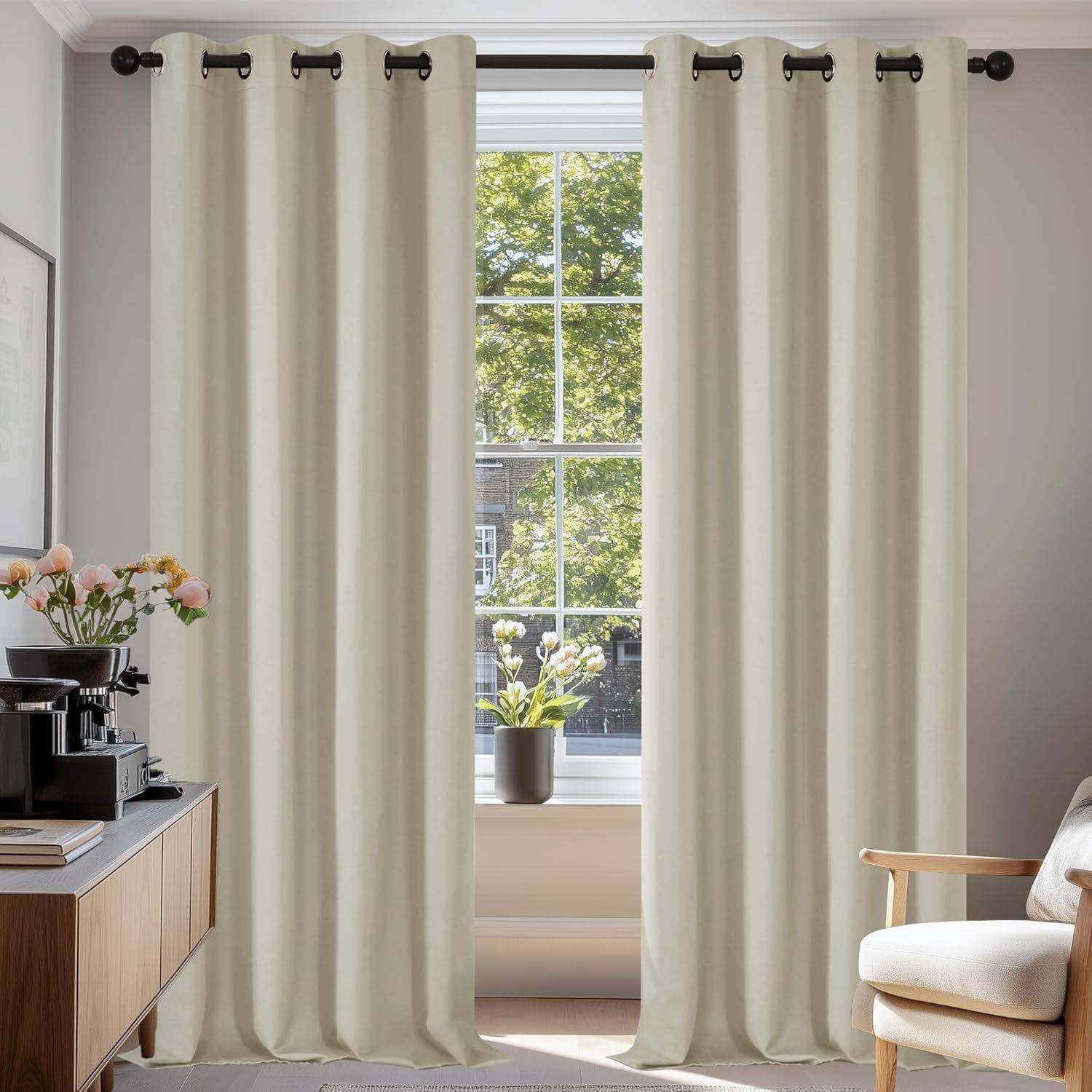 Ein sonnendurchfluteter Raum zeigt beige Vorhänge, die ein Fenster umrahmen, durch das man grüne Blätter sieht. Auf einem Tisch stehen eine Kaffeemaschine und eine Vase mit Blumen.
