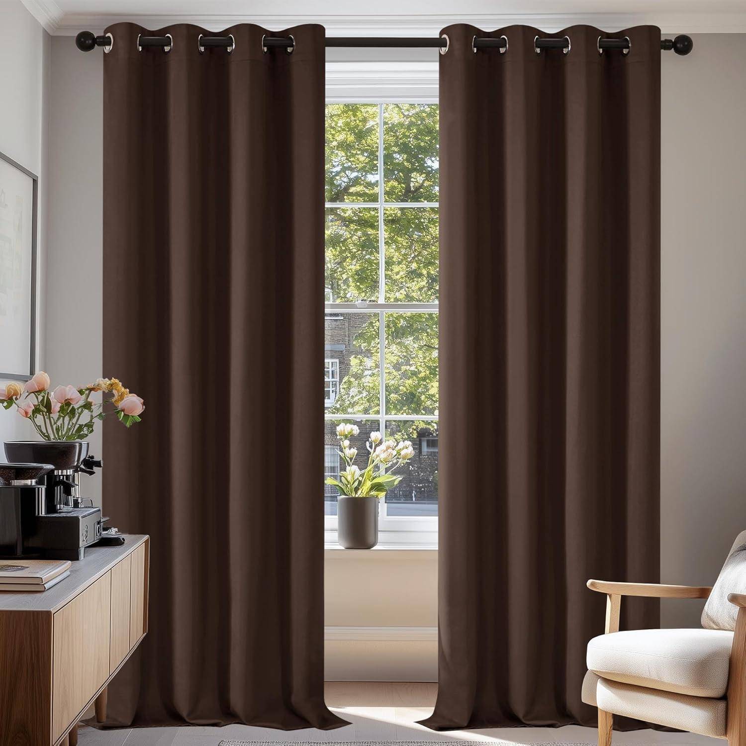 Ein gemütliches Wohnzimmer mit braunen Vorhängen, die ein sonnendurchflutetes Fenster umrahmen. Ein Holzschrank beherbergt eine Kaffeemaschine, eine Tasse und eine Topfpflanze für eine heimelige Atmosphäre.