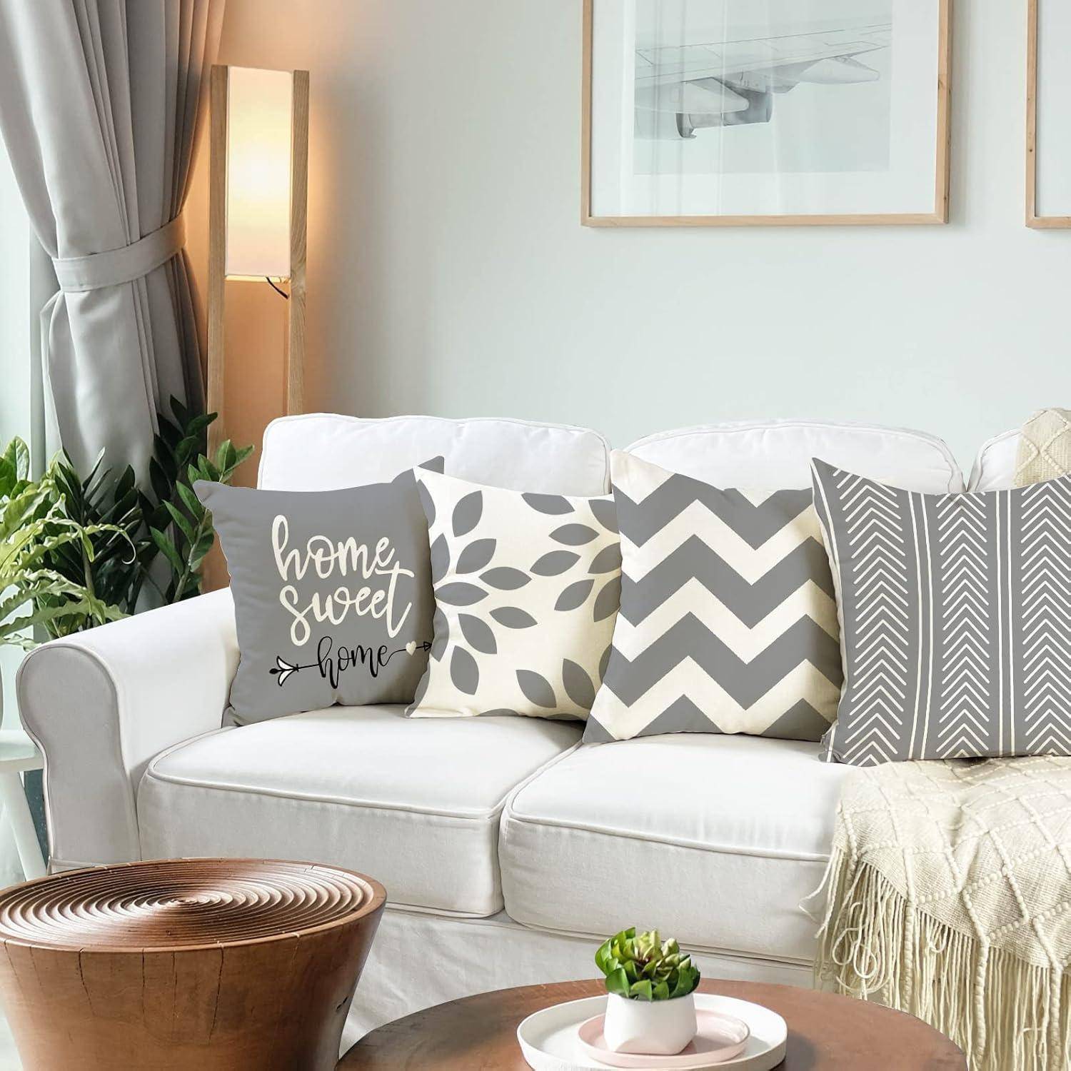 Ein gemütliches Wohnzimmer mit einem weißen Sofa, geschmückt mit dekorativen Kissen, darunter ein Kissen mit dem Text ‚Home Sweet Home', bei sanfter Beleuchtung.