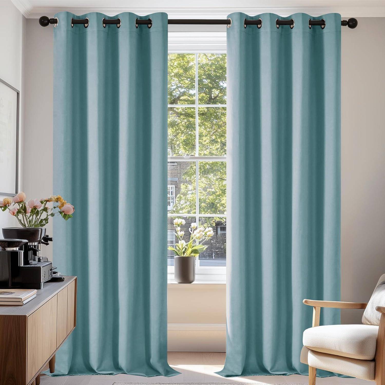 Ein sonnendurchfluteter Raum mit einem Fenster, an dem türkisfarbene Vorhänge hängen, eine kleine Pflanze auf der Fensterbank, eine Kaffeemaschine auf einem Holzseitentisch und ein Stuhl.