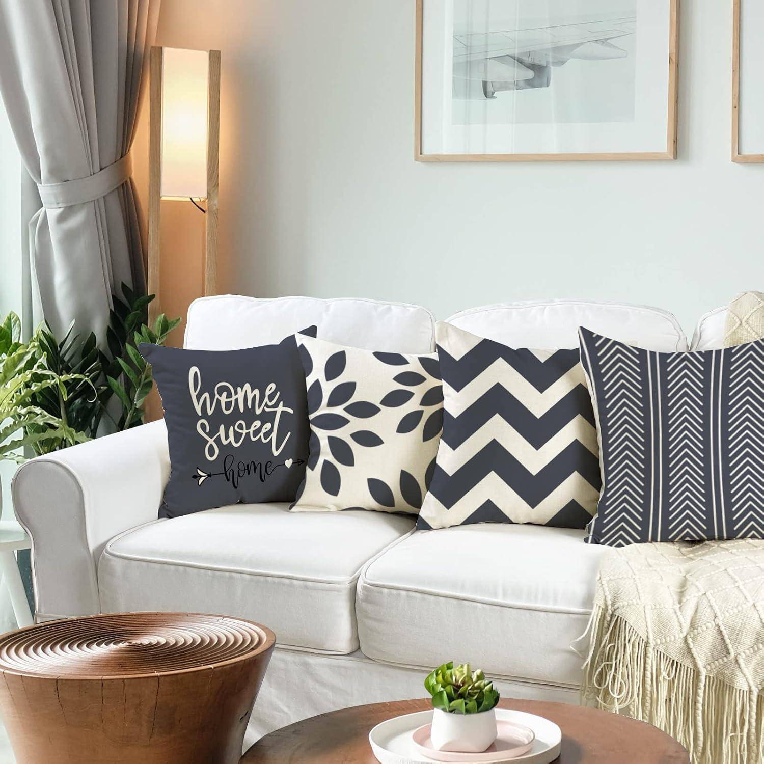 Ein gemütliches Wohnzimmer mit einem weißen Sofa, das mit gemusterten Kissen bestückt ist, einschließlich eines Kissens mit dem Text „home sweet home