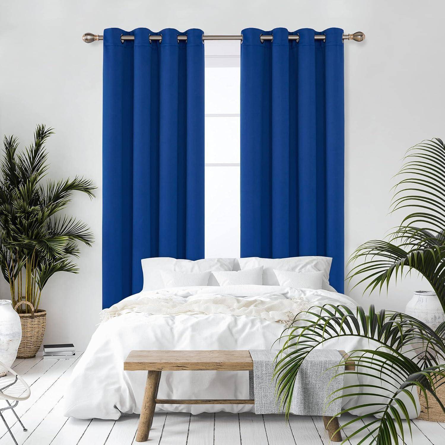 Ein Schlafzimmer mit einem weißen Bett und blauen Vorhängen, umgeben von grünen Topfpflanzen auf einem Holzboden, die eine ruhige, gemütliche Atmosphäre schaffen.