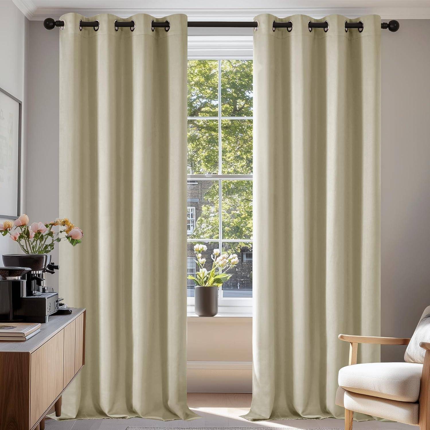 Ein heller Raum mit beigen Vorhängen und Blick auf einen Baum durchs Fenster. Eine Vase mit Blumen steht auf der Fensterbank, und ein kleiner Tisch mit weiteren Blumen befindet sich in der Nähe.