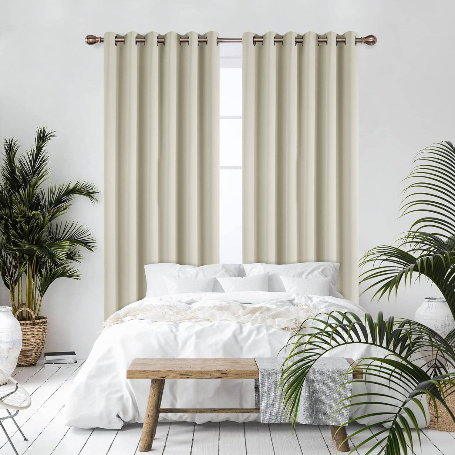 Ein heller Schlafzimmerbereich mit einem ordentlich gemachten Bett, einer Holzbank am Fußende, großen Topfpflanzen und weißen Vorhängen, die das Fenster verdecken.