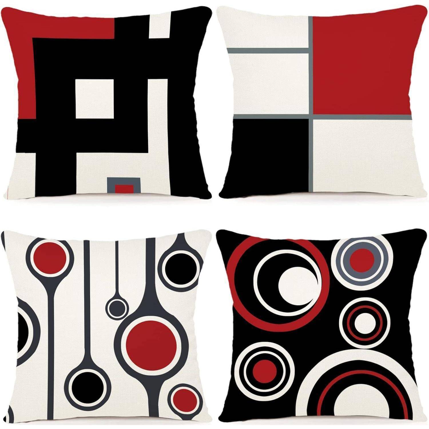Vier Kissen mit geometrischen Designs in Schwarz, Weiß, Rot und Grau; Muster umfassen Quadrate, Rechtecke und Kreise.