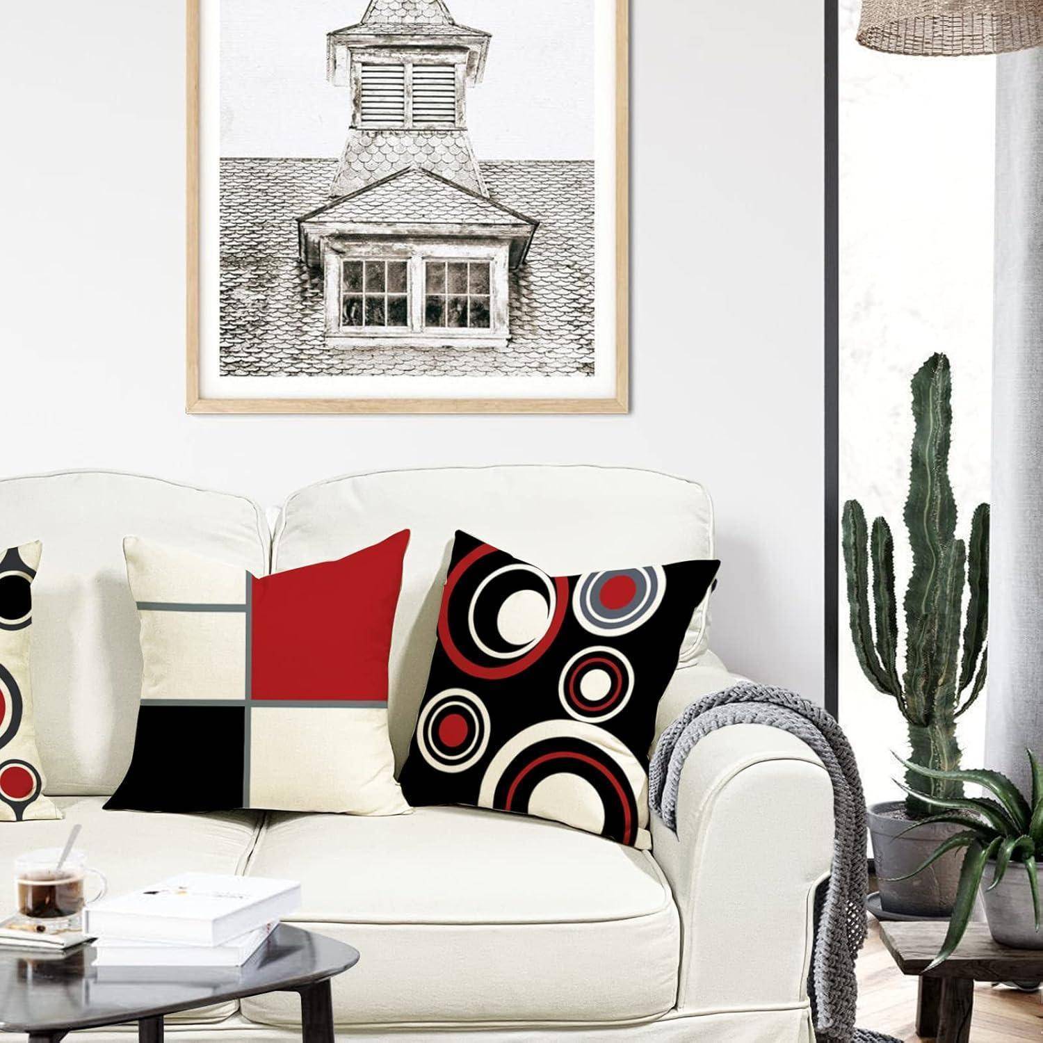 Ein gemütliches Wohnzimmer mit einem cremefarbenen Sofa, geschmückt mit bunten geometrisch gemusterten Kissen. Ein gerahmtes architektonisches Foto hängt an der Wand.