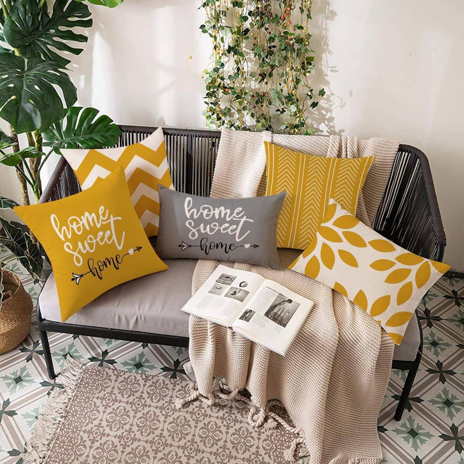 Ein modernes Wohnzimmer mit einem grauen Sofa, gelb-grauen gemusterten Kissen, einer cremefarbenen Decke, einer Zeitschrift, Pflanzen und einem gefliesten Boden.