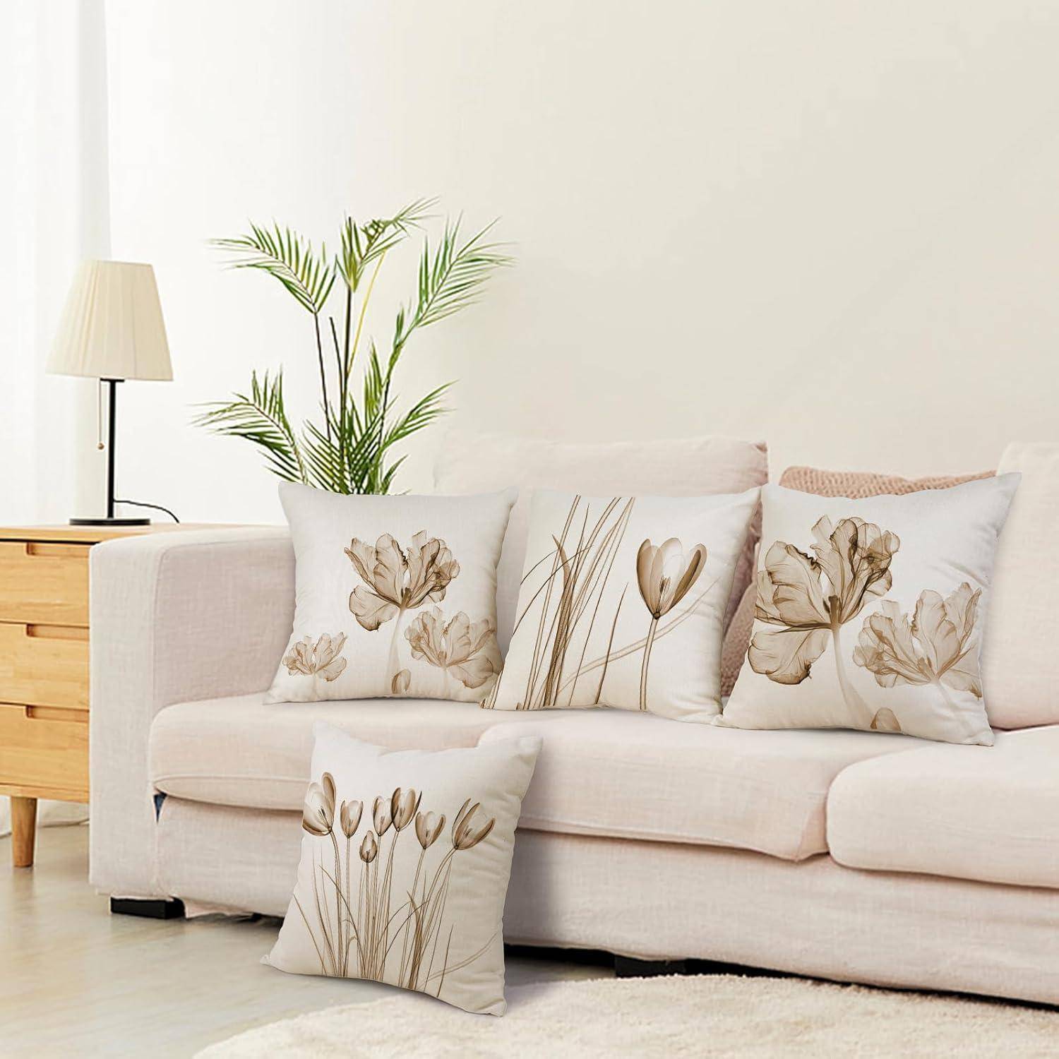 Ein neutral gestaltetes Wohnzimmer zeigt ein weißes Sofa, das mit blumenmustrigen Kissen geschmückt ist, einen Holzseitentisch, eine Lampe und eine Topfpflanze.