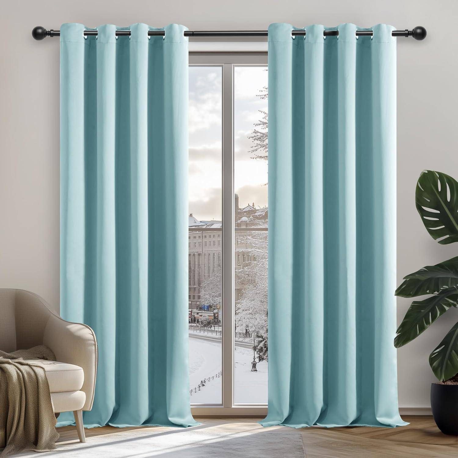 Blaue Vorhänge am Fenster enthüllen eine verschneite Stadtlandschaft. Ein beiger Stuhl und eine grüne Pflanze in der Nähe schaffen eine gemütliche Inneneinrichtung.
