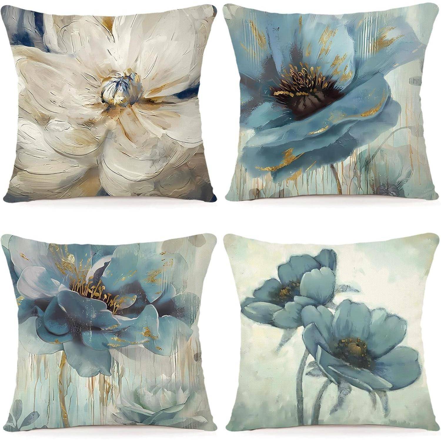 Vier dekorative Kissen, die jeweils künstlerische Blumendesigns in weichen Blau- und Beigetönen präsentieren und so eine elegante und beruhigende Ästhetik erzeugen.