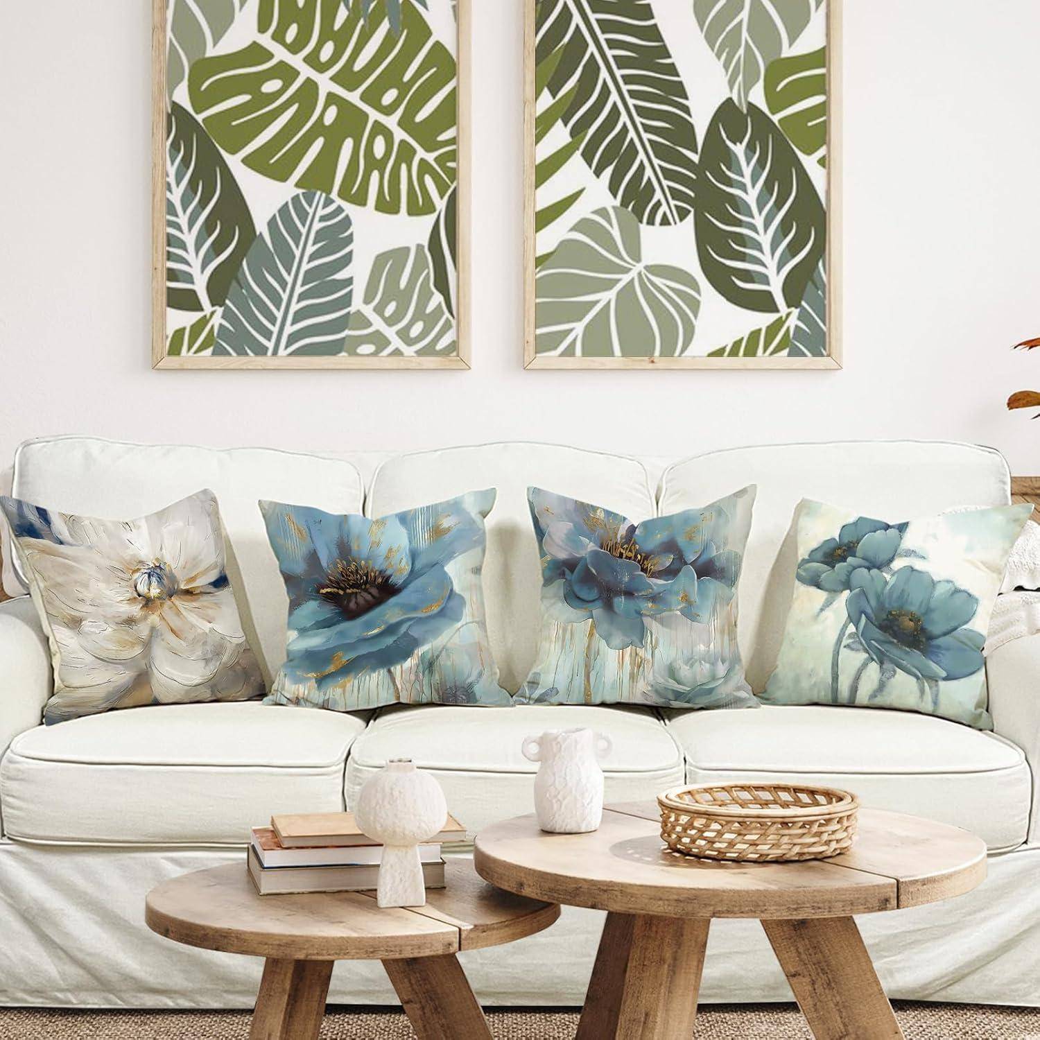 Ein gemütliches Wohnzimmer mit einem weißen Sofa, das mit Blumenkissen geschmückt ist. Zwei Tische tragen Dekorationsgegenstände. Darüber erhöhen gerahmte botanische Kunstwerke den Raum.