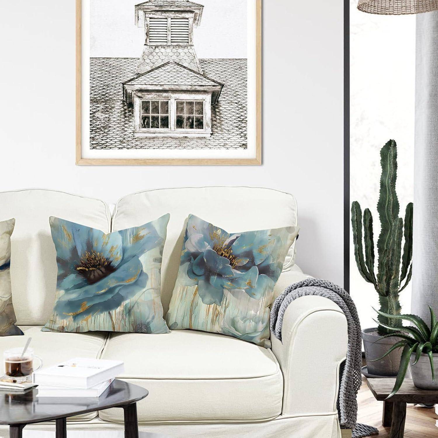 Ein gemütliches Wohnzimmer mit einem weißen Sofa, ausgestattet mit blauen Blumenkissen und einem kleinen Couchtisch. Ein gerahmtes architektonisches Foto hängt über dem Sofa.