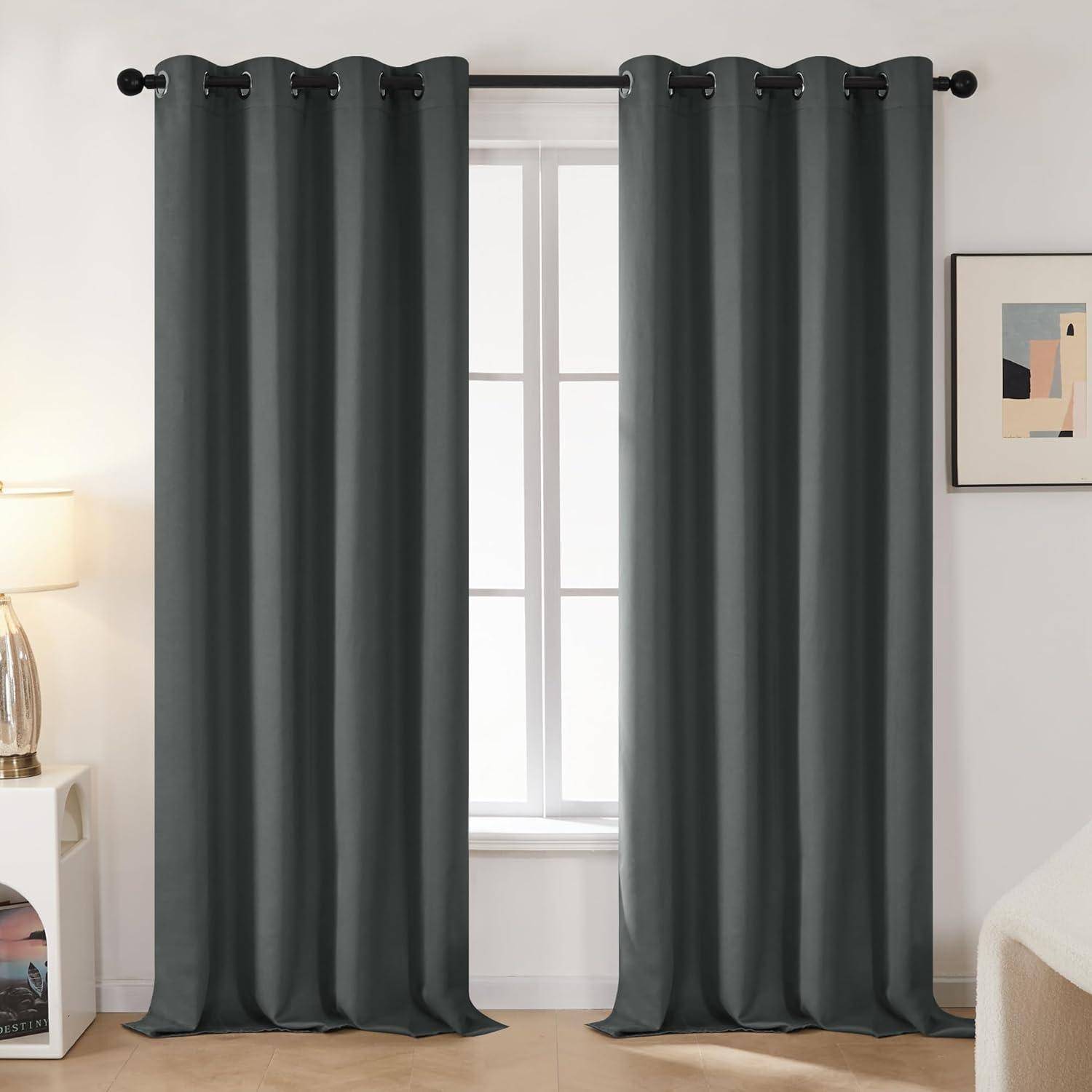 Ein Raum mit zwei grauen Vorhängen, die ein Fenster umrahmen. Eine Lampe befindet sich links, und Kunstwerke hängen an der rechten Wand. Natürliches Licht durchflutet den Raum.