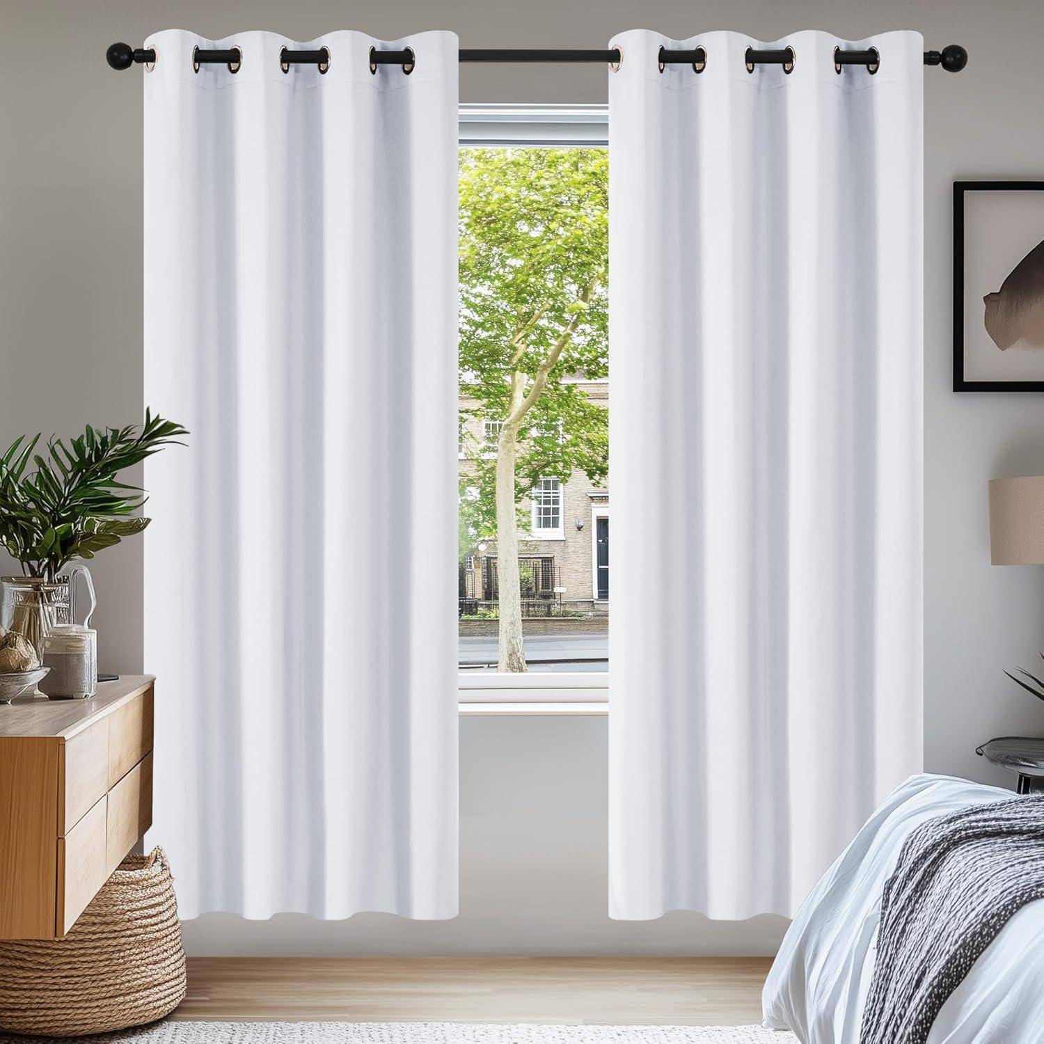Weiße Vorhänge hängen in einem Raum mit einer großen Fensteraussicht auf eine baumgesäumte Straße, eingerahmt von minimalistischer Dekoration, einschließlich eines kleinen Beistelltisches mit einer Pflanze.