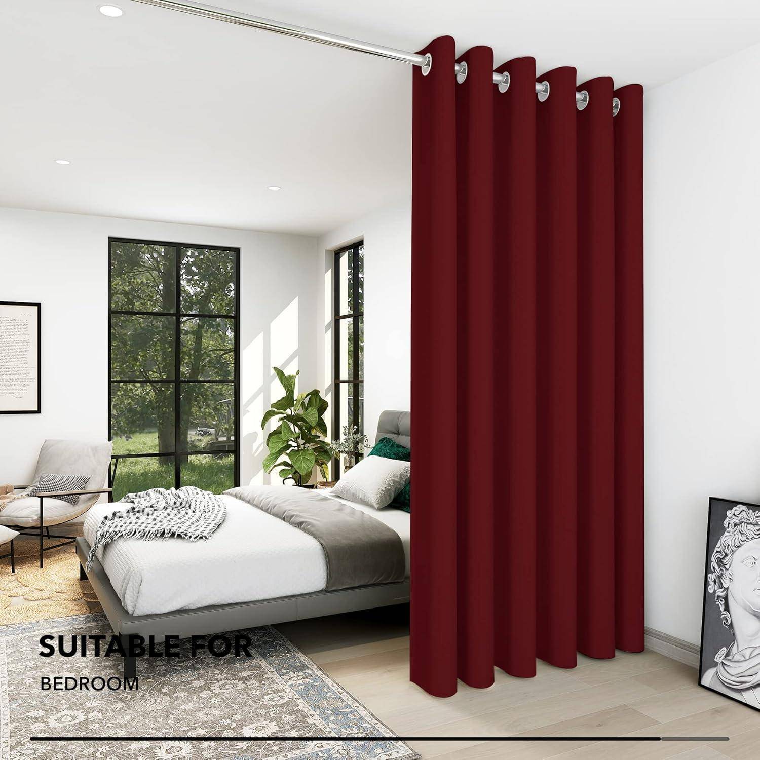 Ein Schlafzimmer mit einem ordentlich bezogenen weißen Bett, burgunderroten bodenlangen Vorhängen und einer Topfpflanze in der Nähe eines sonnendurchfluteten Fensters.
