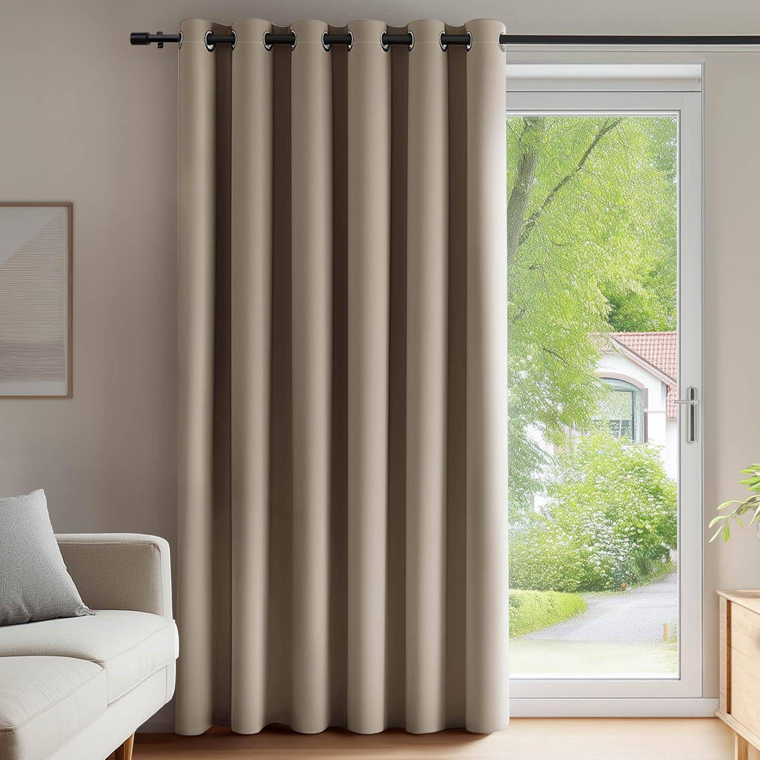 Ein beige Vorhang verdeckt ein bodentiefes Fenster mit Blick auf einen grünen Garten und ein Haus. Auf der linken Seite ist ein Teil eines Sofas zu sehen.