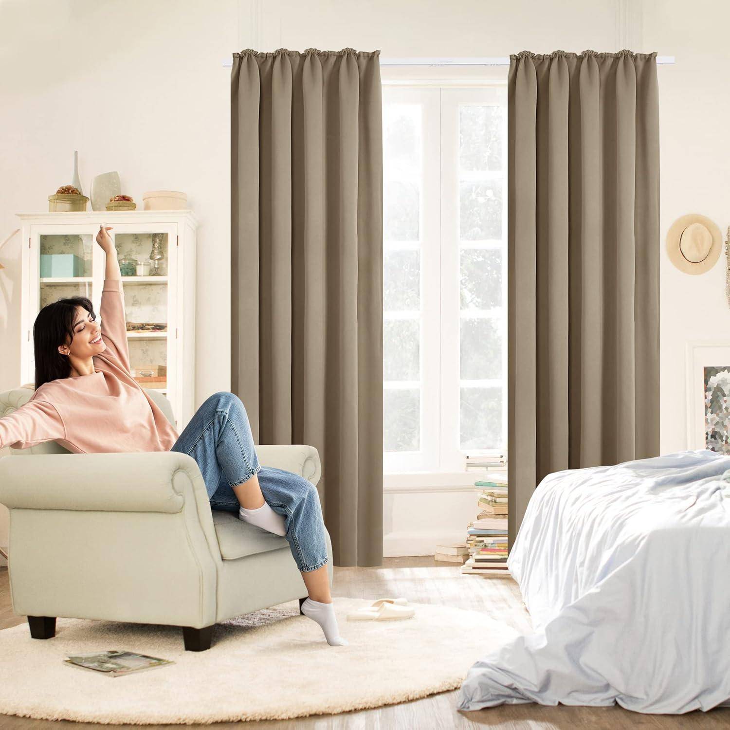 Eine Person sitzt auf einem hellgrünen Sessel in einem gemütlichen Schlafzimmer mit beigen Vorhängen, weißen Wänden und einem Bett, wodurch eine ruhige und entspannte Atmosphäre entsteht.