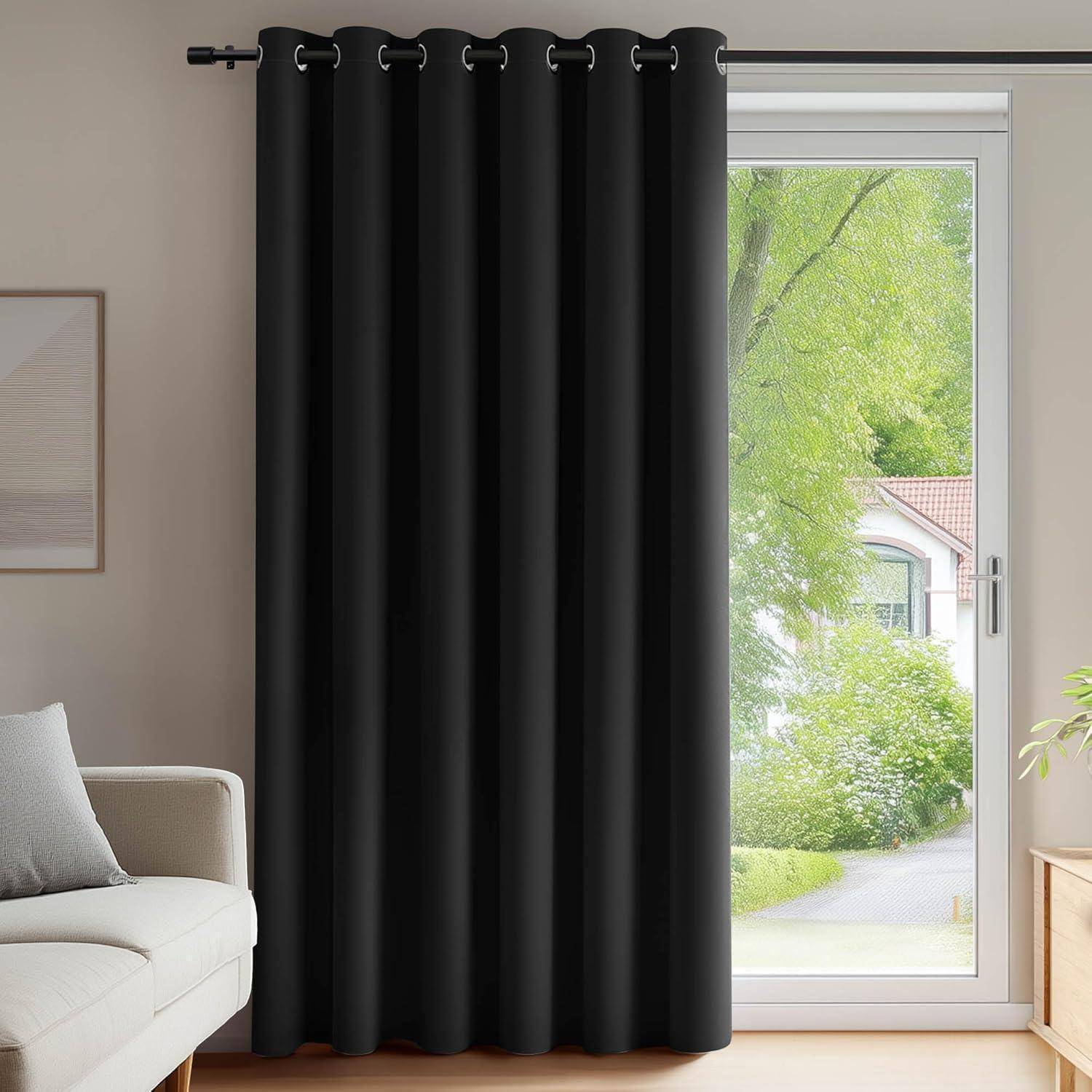 Verdunkelungsvorhänge, die an einem Fensterrahmen hängen und teilweise den Blick auf einen sonnigen Garten mit Bäumen und einem Haus im Hintergrund verdecken.