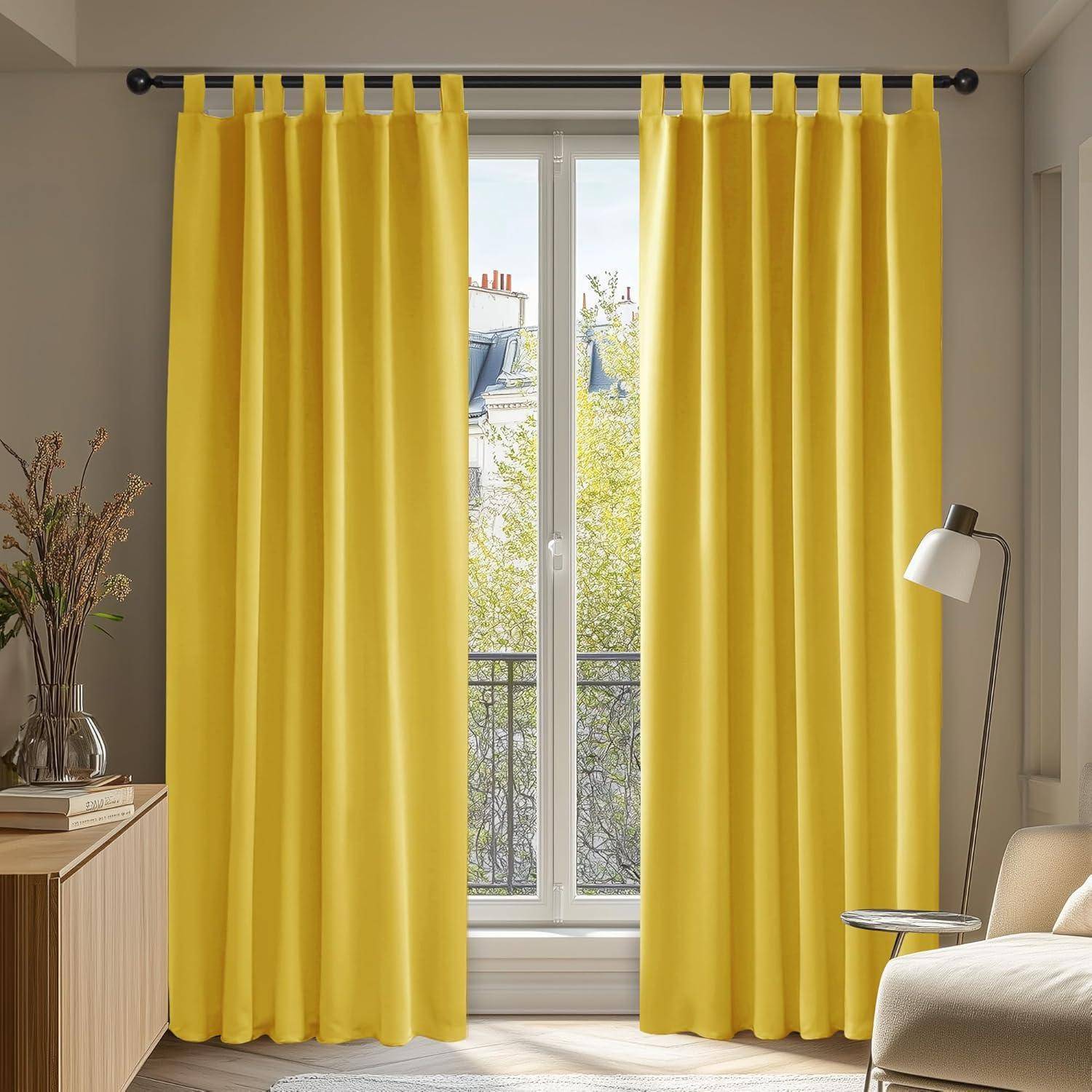 Ein Raum mit leuchtend gelben Vorhängen, die vor einem Fenster hängen und weiches natürliches Licht hereinlassen. Ein kleiner runder Tisch und eine Lampe befinden sich in der Nähe.