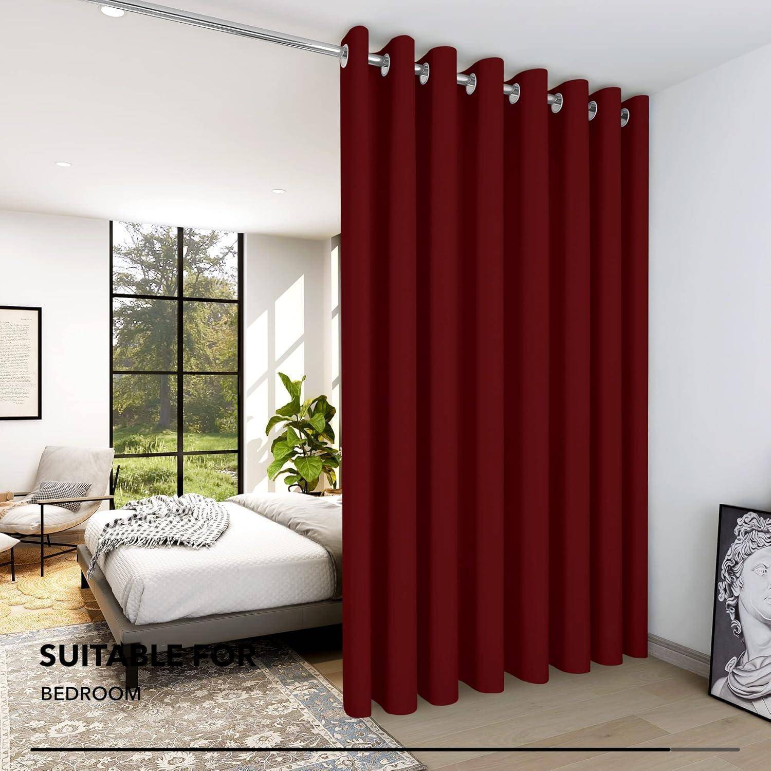 Ein Schlafzimmer mit einem roten Vorhang, der den Raum teilt, mit einem Bett, das mit einer weißen Decke und grauen Akzenten ausgestattet ist, neben einem großen Fenster mit Grünpflanzen draußen.