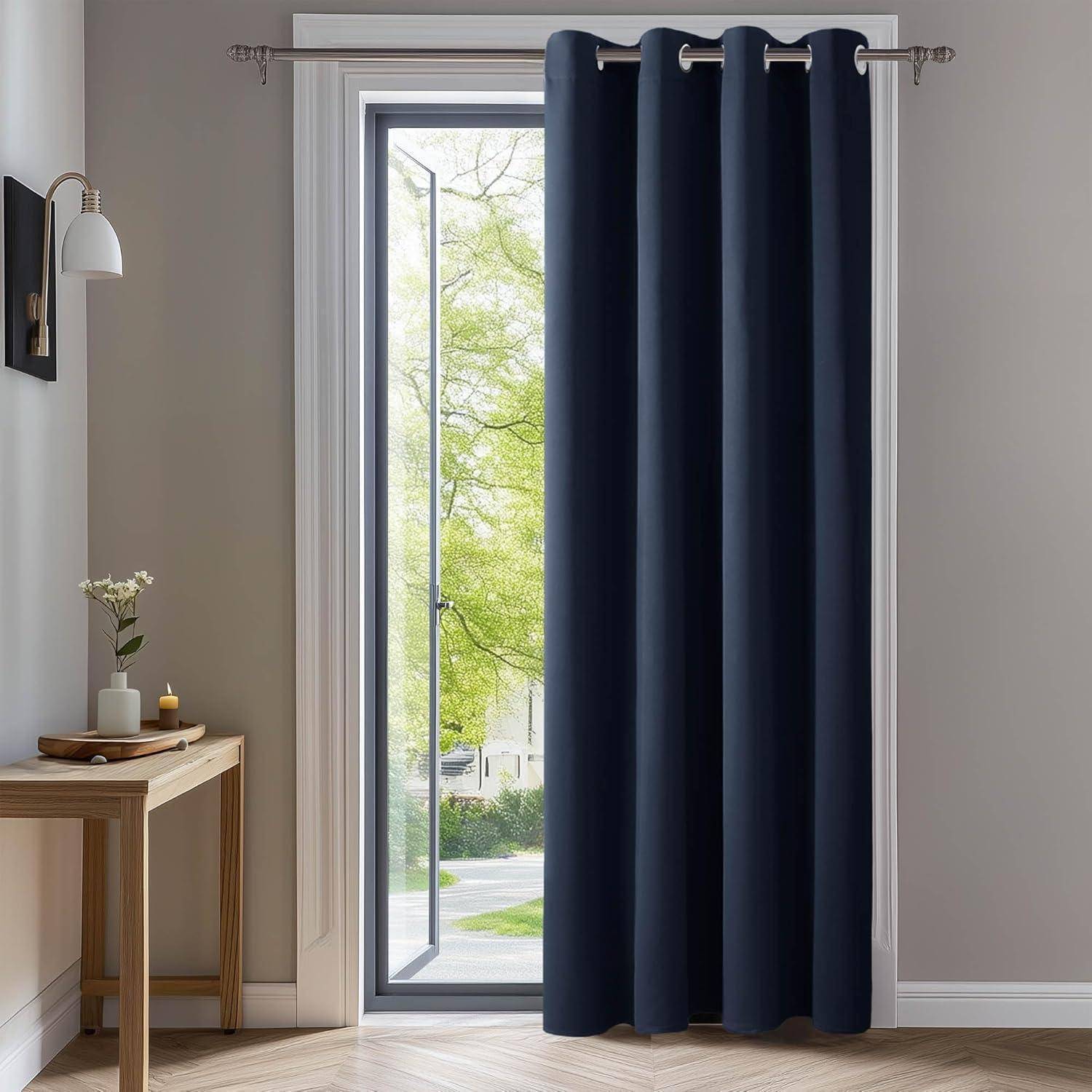 Ein Raum mit einem Holztisch, einer Topfpflanze und einer Kerze links. Ein großes Fenster mit dunkelblau Vorhängen, die teilweise zurückgezogen sind und einen Blick auf Bäume draußen freigeben.