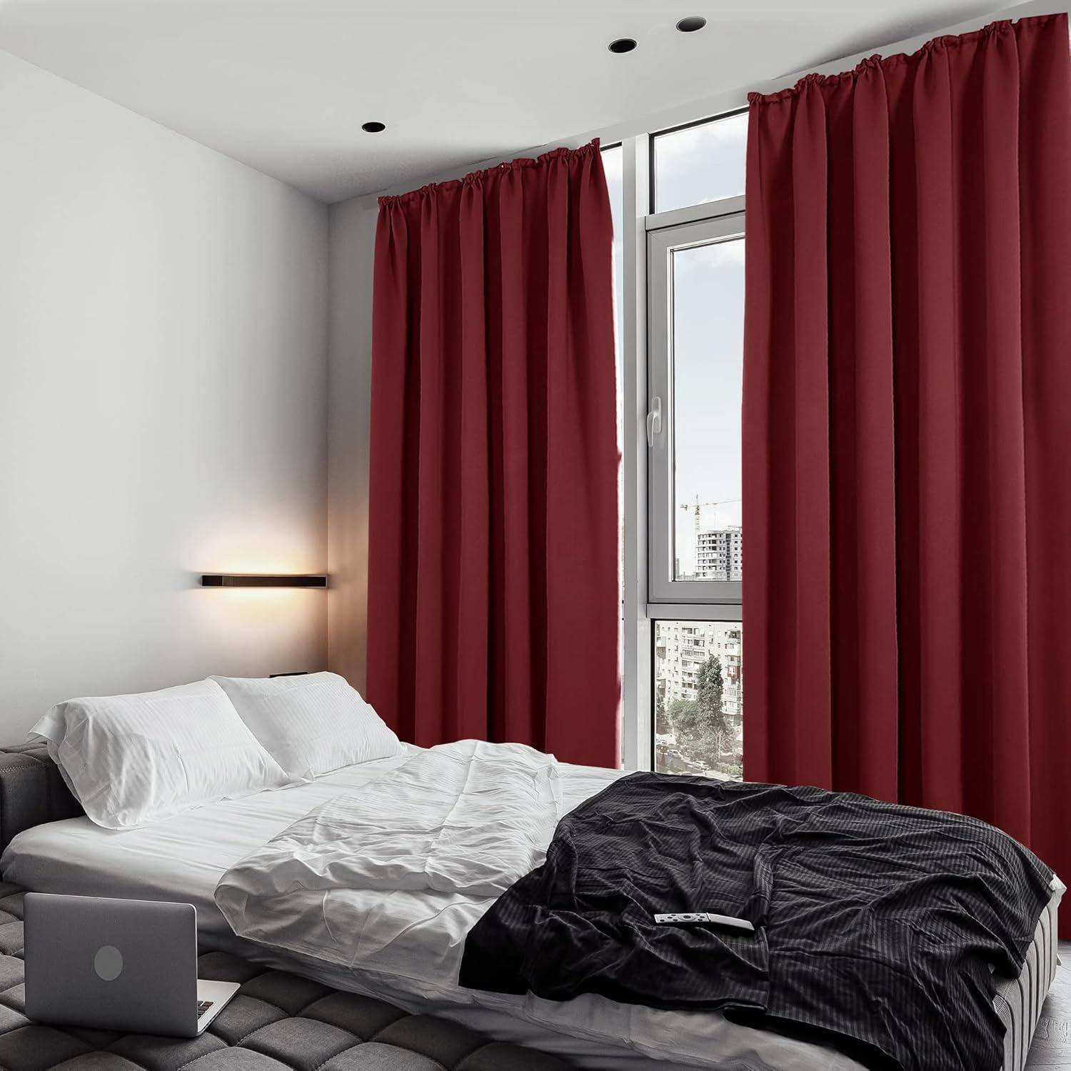 Ein aufgeräumtes Schlafzimmer mit einem weißen Bett, roten Vorhängen und einem großen Fenster mit Blick auf Stadtgebäude, das eine minimalistische und moderne Atmosphäre schafft.
