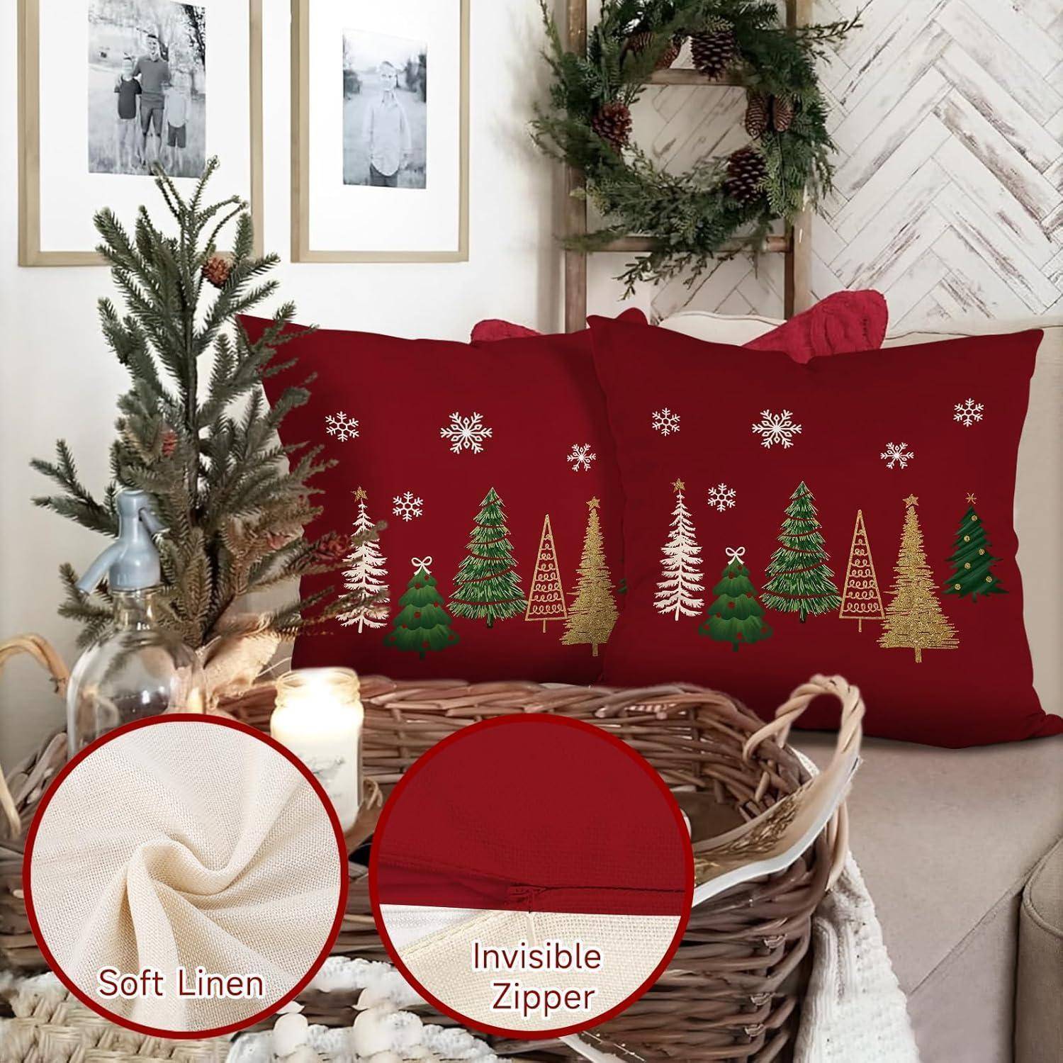 Rote Kissenbezüge mit dekorativen grünen und goldenen Weihnachtsbäumen und Schneeflocken auf einem Sofa. Zusätzliche Details zeigen 'Soft Linen' und 'Unsichtbarer Reißverschluss'.