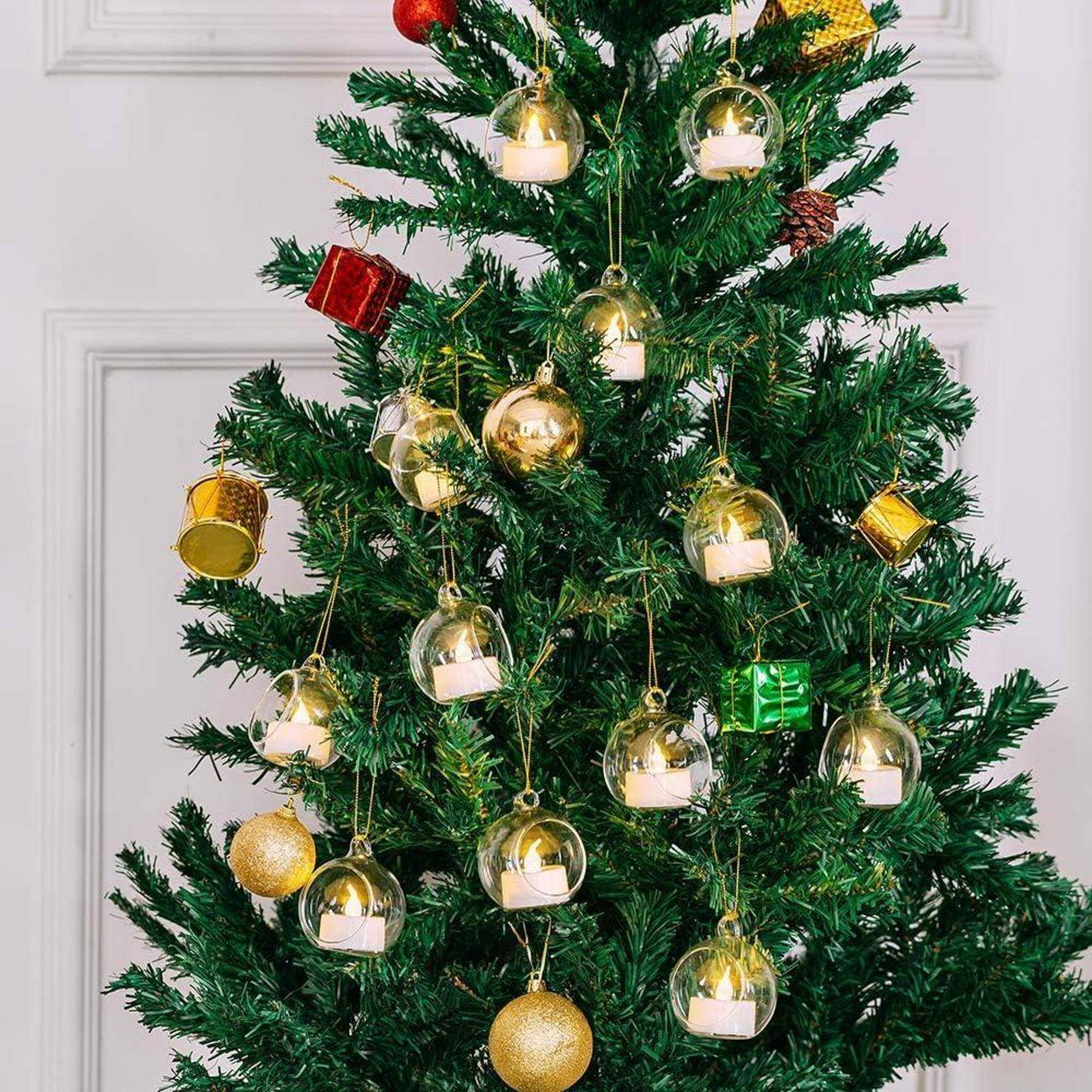 Ein geschmückter Weihnachtsbaum mit goldenen Kugeln, kleinen verpackten Geschenken und transparenten Kerzenhalter-Ornamenten, die von seinen Zweigen hängen.