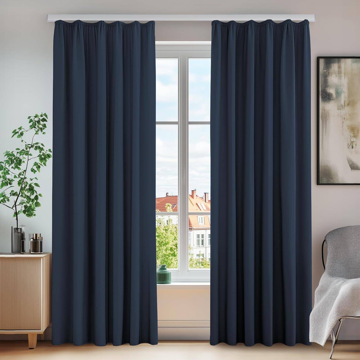 Ein heller Raum mit einem großen Fenster, das dunkle Vorhänge aufweist, ein kleiner Schrank mit Pflanzen links und ein teilweise gerahmtes Kunstwerk rechts.