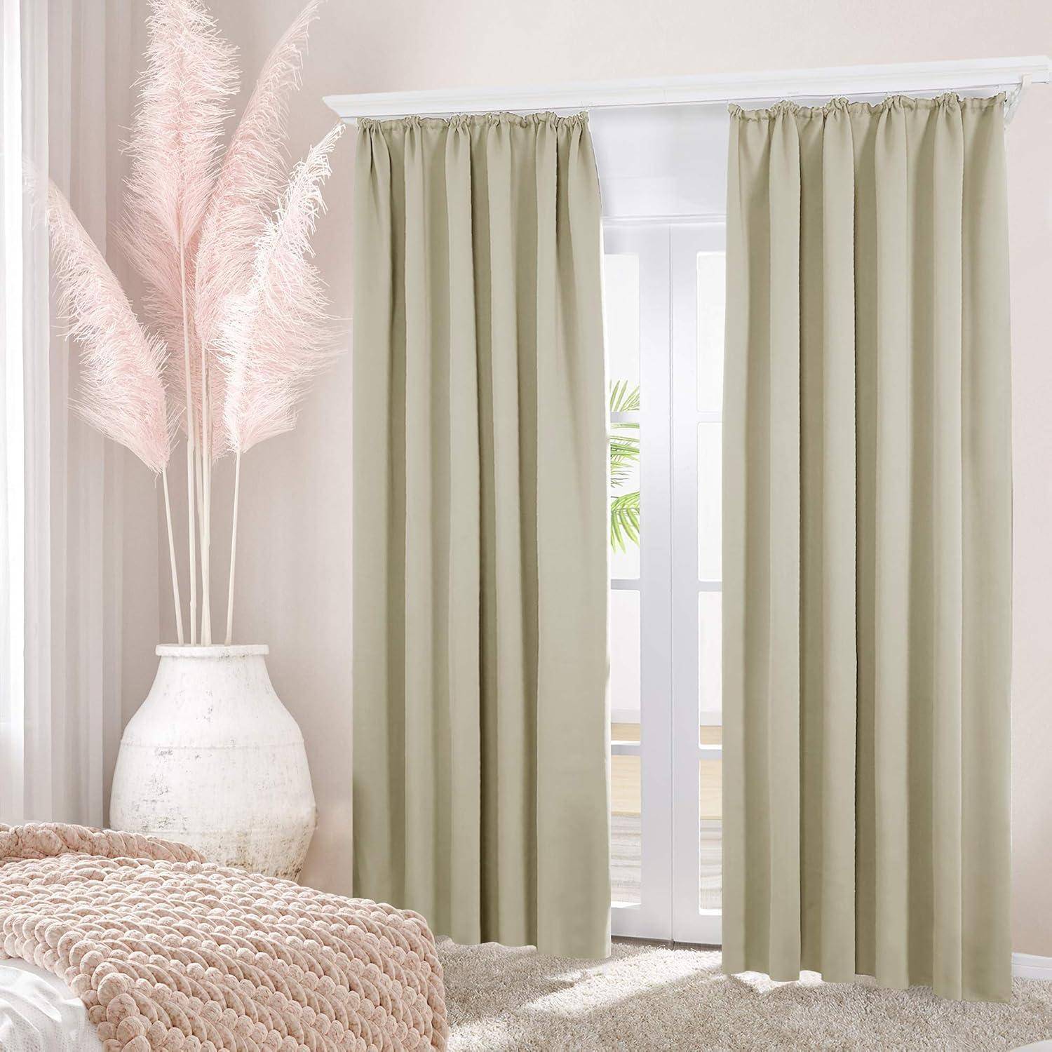 Beige Vorhänge verdecken ein hohes Fenster, das teilweise geöffnet ist und Sonnenlicht sowie einen Blick auf Grünpflanzen freigibt. Eine strukturierte rosa Decke bedeckt das Bett.