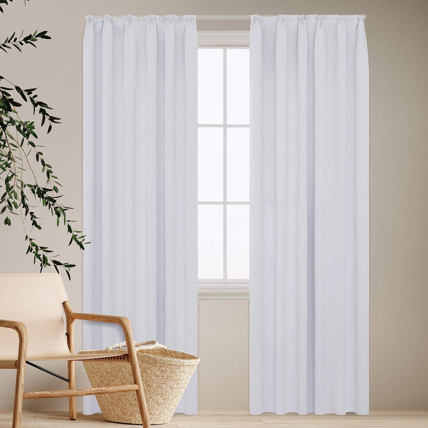 Weiße Vorhänge hängen neben einem Fenster, mit einer Pflanze und einem Korbstuhl in der Nähe, was eine minimalistische und ruhige Raumatmosphäre schafft.