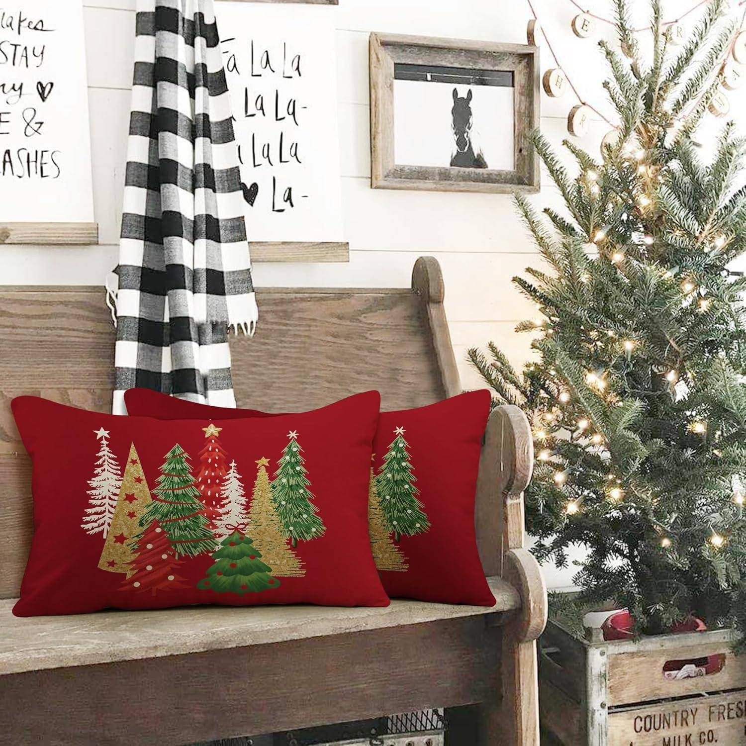 Ein gemütlicher Raum mit einer Holzbank, die mit roten Kissen mit festlichen Baumdesigns geschmückt ist. Ein Weihnachtsbaum und Wandkunst vervollständigen die Weihnachtsdekoration.