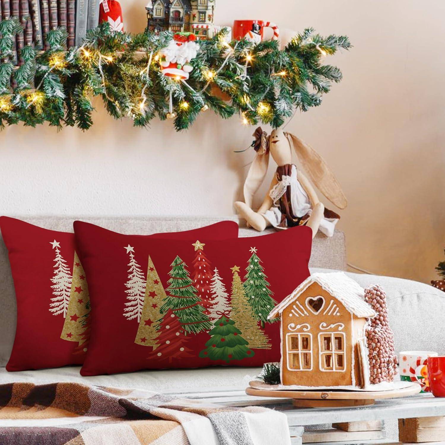 Ein gemütliches Wohnzimmer mit Weihnachtsatmosphäre präsentiert eine Girlande mit Weihnachtskugeln, dekorierte Kissen mit Tannenbaummotiven und ein Lebkuchenhaus auf dem Tisch.