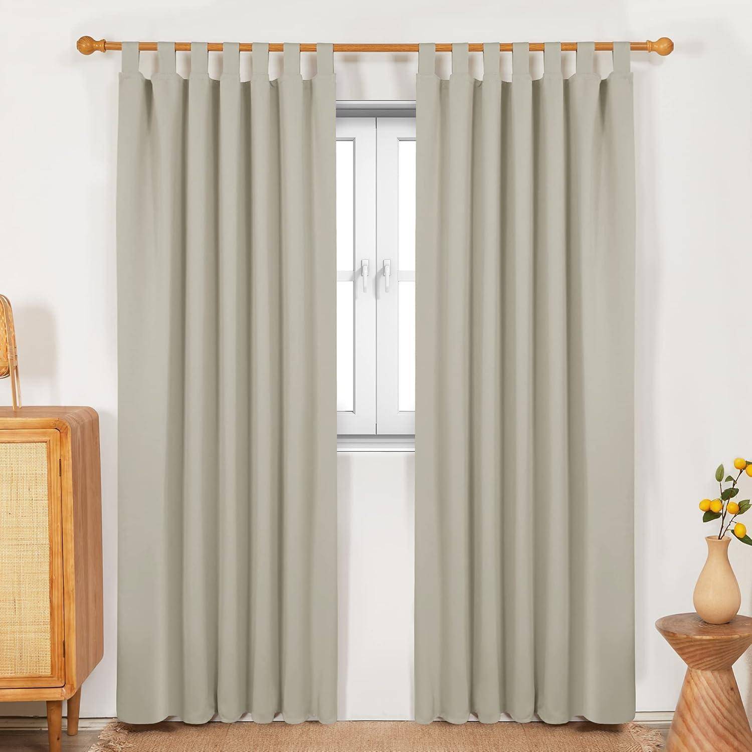 Ein Fenster mit geschlossenen hellgrauen Vorhängen, links flankiert von einem Holzschrank und rechts von einem kleinen runden Tisch mit einer Blumenvase.