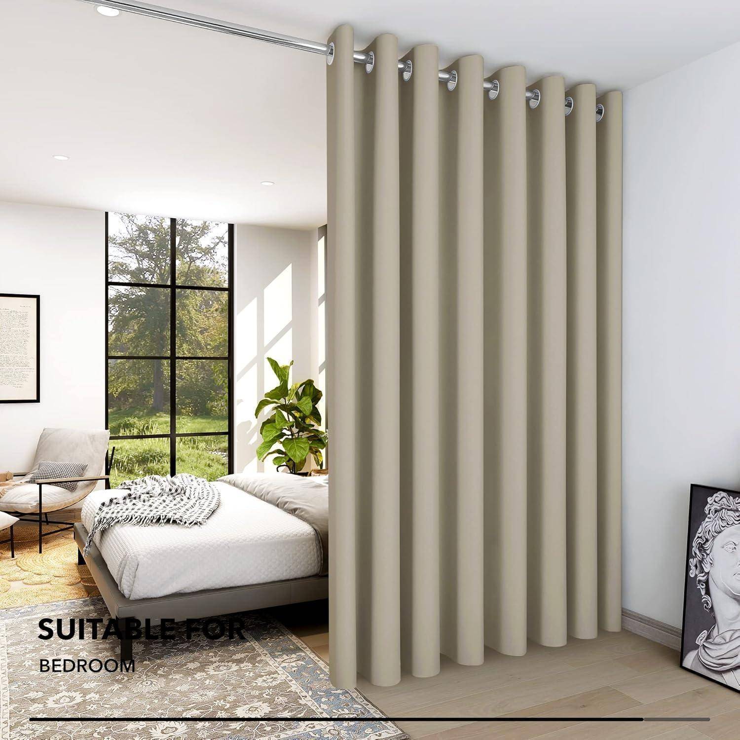 Ein modernes Schlafzimmer mit einem großen beigen Vorhang, der den Raum teilt, ausgestattet mit einem Bett, einem Stuhl und natürlichem Licht, das durch hohe Fenster hereinfällt.