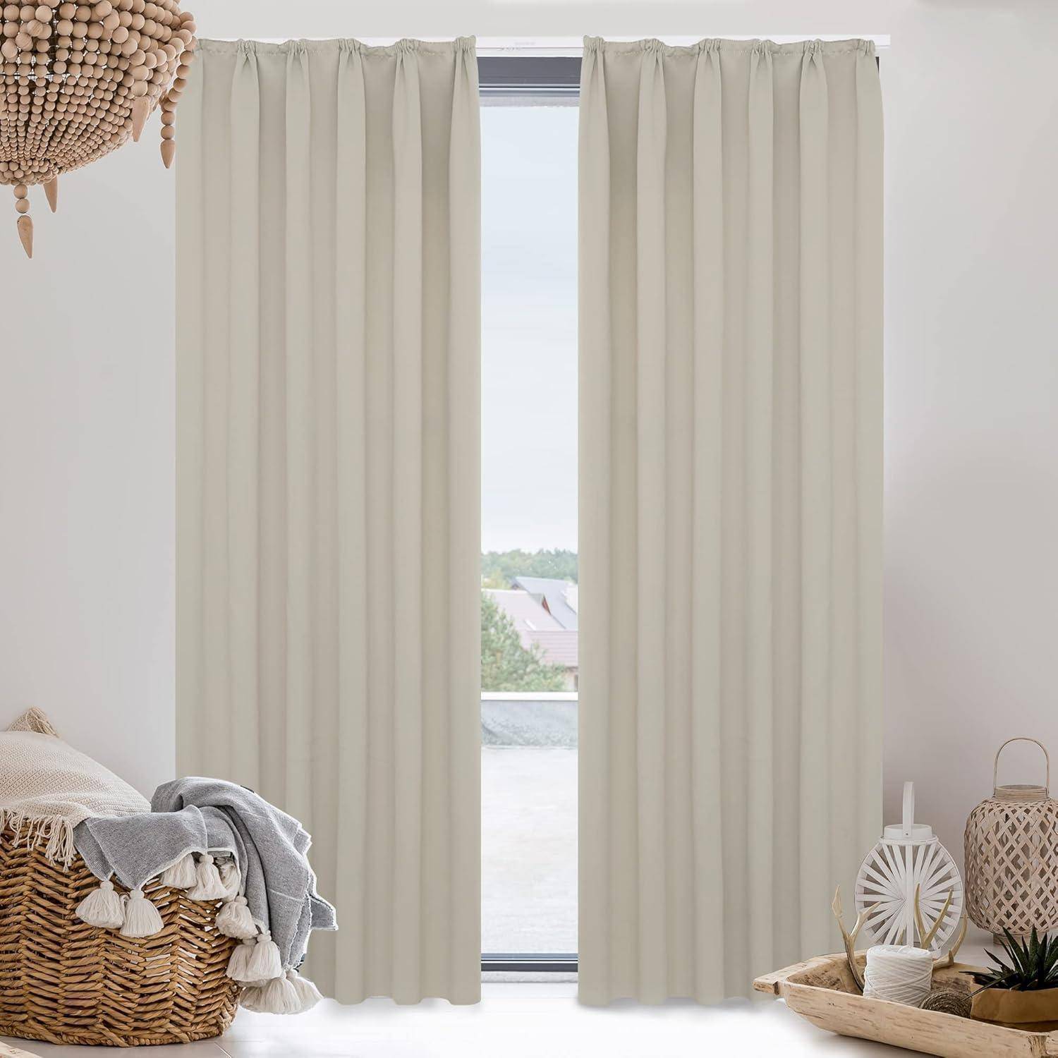 Ein Wohnzimmerfenster mit hellbeigen Vorhängen, einem gewebten Korb mit Quasten, einem beigen Sofa mit grauem Stoff und einem weißen Topf mit einer Pflanze.