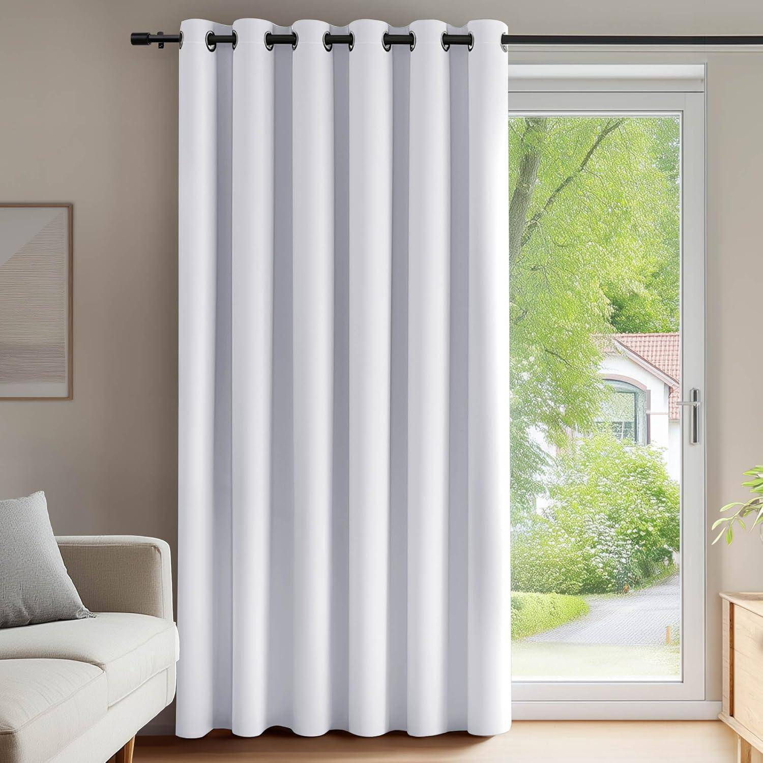 Ein weißer Vorhang hängt vor einem Fenster, teilweise geöffnet und gibt den Blick auf einen grünen Garten und ein Haus draußen frei.
