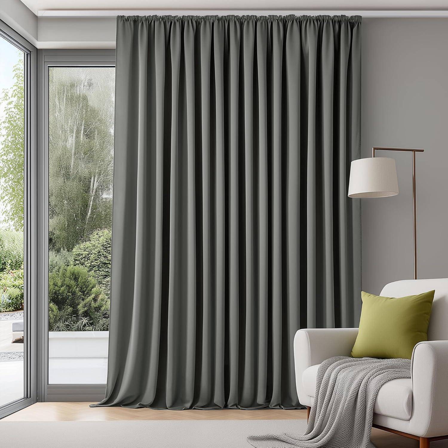 Eine gemütliche Ecke des Wohnzimmers zeigt einen hellgrauen Sessel mit einem grünen Kissen, eine weiße Stehlampe und graue Vorhänge neben einem großen Fenster mit Blick in den Garten.