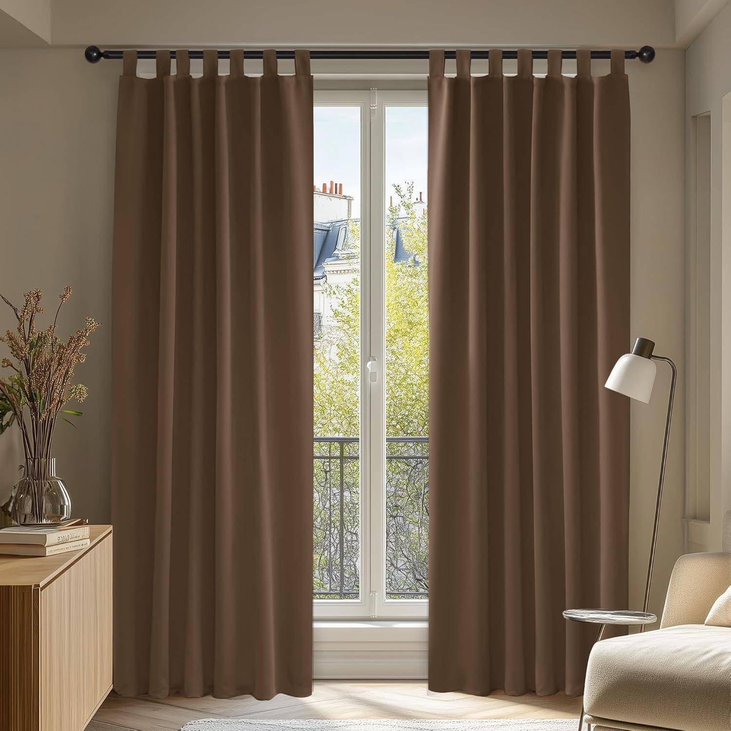Braune Vorhänge hängen vor einem hellen Fenster, mit Pflanzen und einer Stehlampe in der Nähe, wodurch eine gemütliche Innenraumszene entsteht.