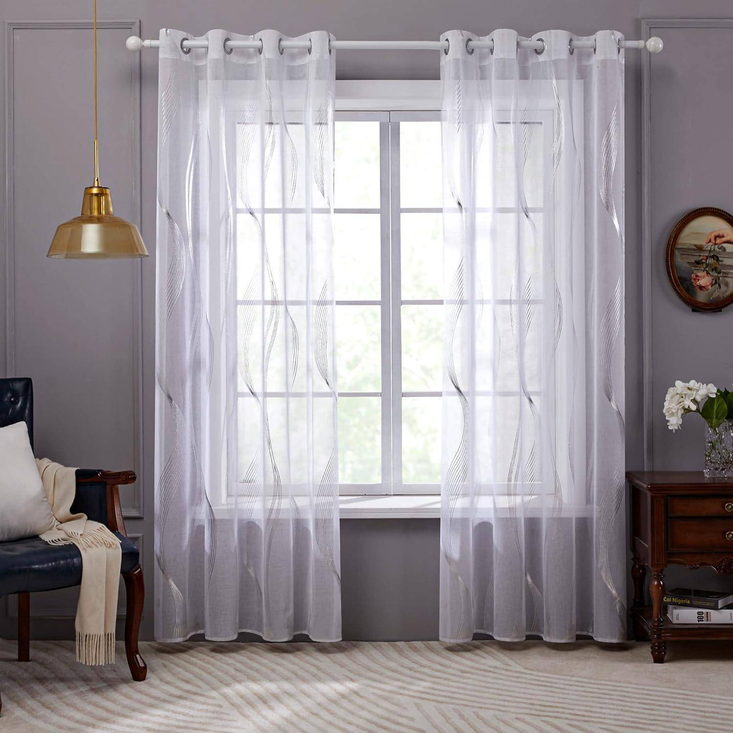 Ein Fenster mit durchsichtigen weißen Vorhängen lässt weiches Licht herein. Ein gemütlicher Sessel mit einer Decke steht links, und ein kleiner Tisch mit Blumen steht rechts.