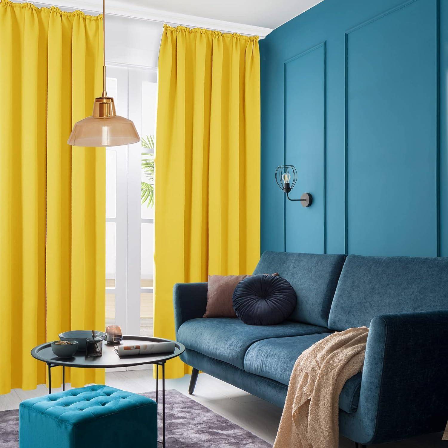 Ein gemütliches Wohnzimmer mit hellgelben Vorhängen, einem blauen Sofa und einem runden Couchtisch, das eine lebendige und einladende Atmosphäre schafft.