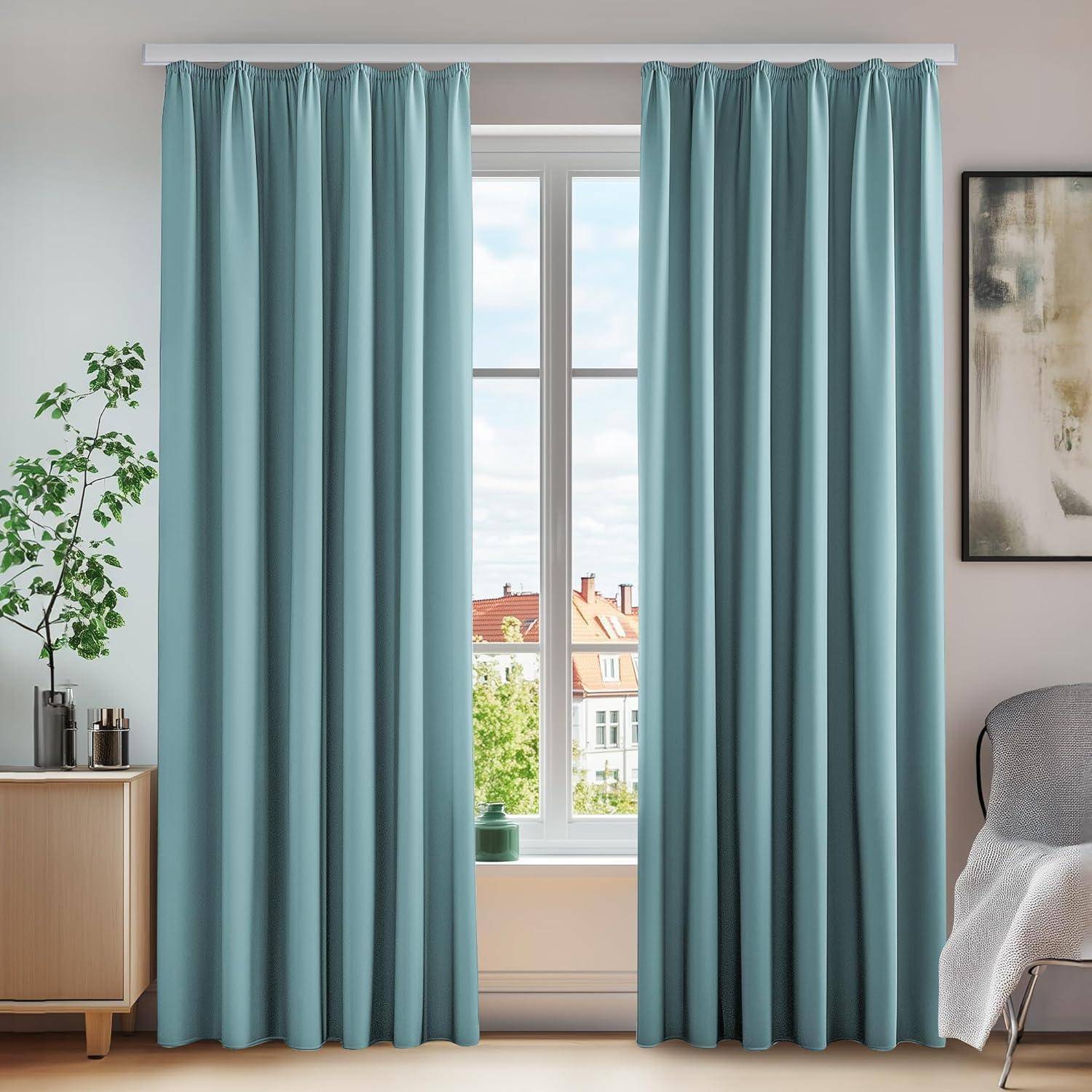 Hellblaue Vorhänge hängen an einem Fenster, mit einem kleinen Baum auf einer Kommode links. Das Fenster bietet einen Blick auf Dächer draußen.