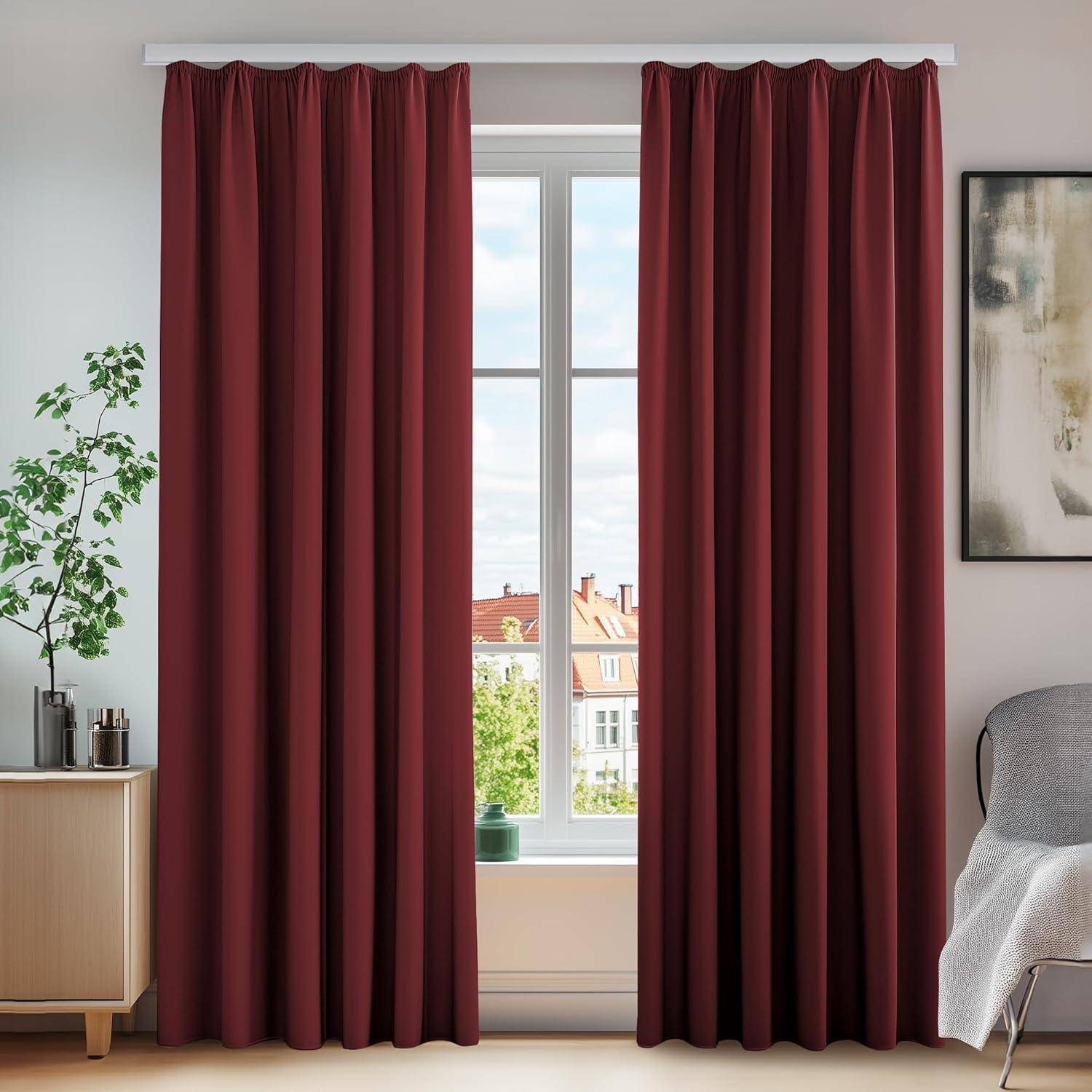 Ein Raum mit burgunderroten Vorhängen, die ein Fenster umrahmen, durch das Dächer zu sehen sind, eine kleine Pflanze auf einem hellholzfarbenen Ständer und eine teilweise Ansicht eines Stuhls.