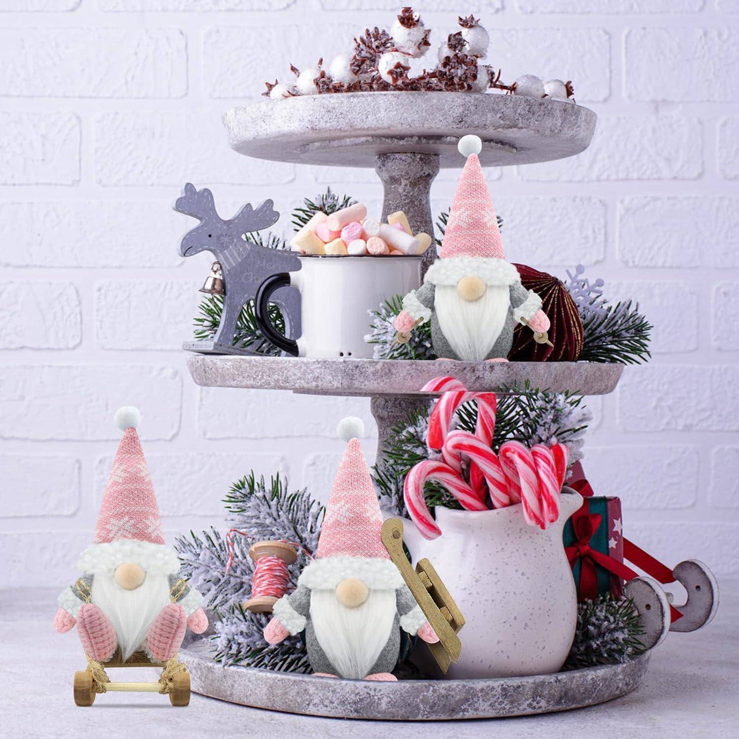Zweistöckiges Tablett mit Weihnachtsdekoration: eine Rentierstatue, eine Tasse mit Marshmallows, ein Krug mit Zuckerstangen, Tannenzweige und Wichtel.
